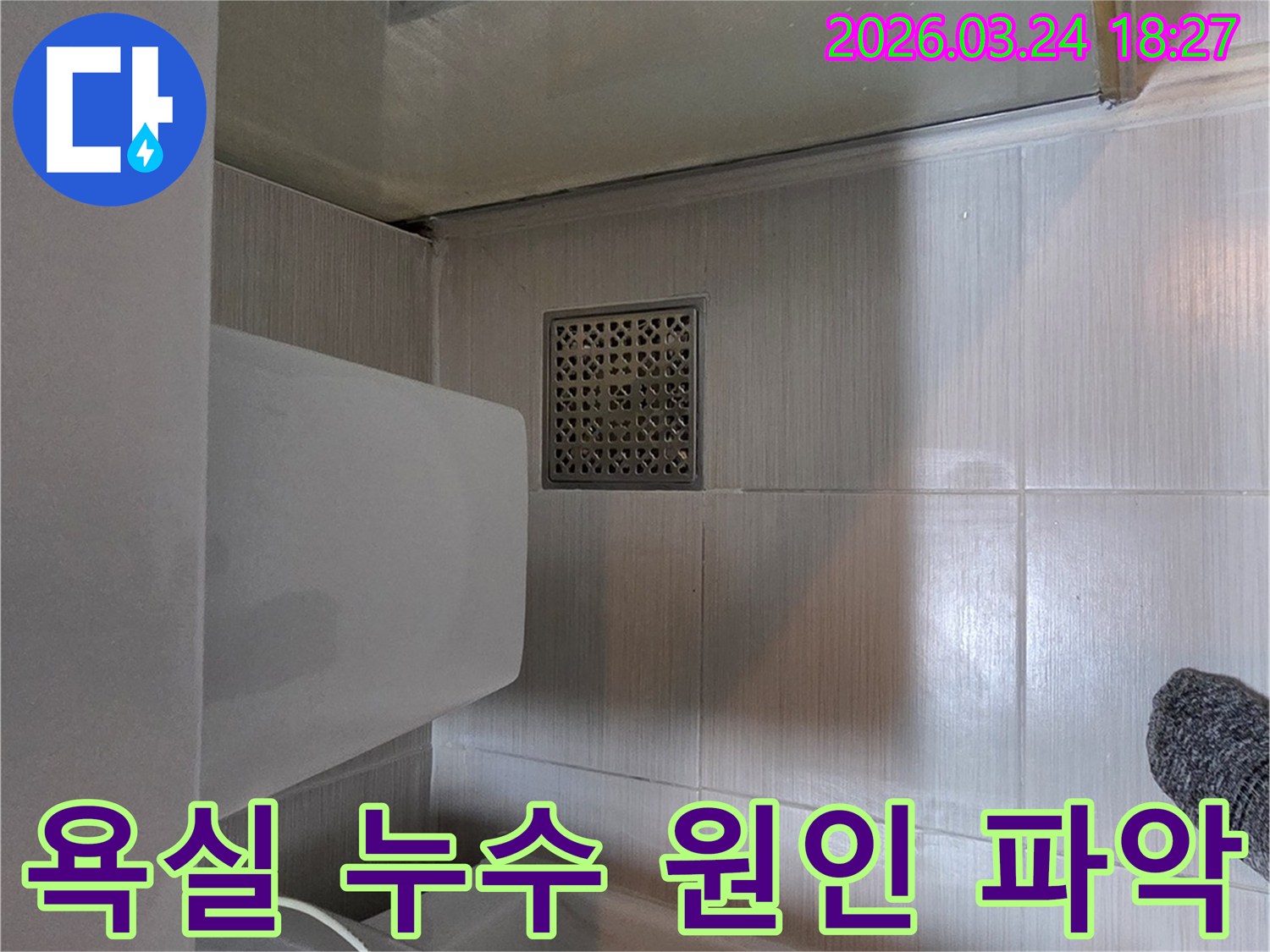 동두천시 누수공사 현장에서-욕실 바닥의 누수 원인을 파악하기 위해-배수구와 주변 타일 상태를-면밀히 점검하는-전문가의 모습입니다.