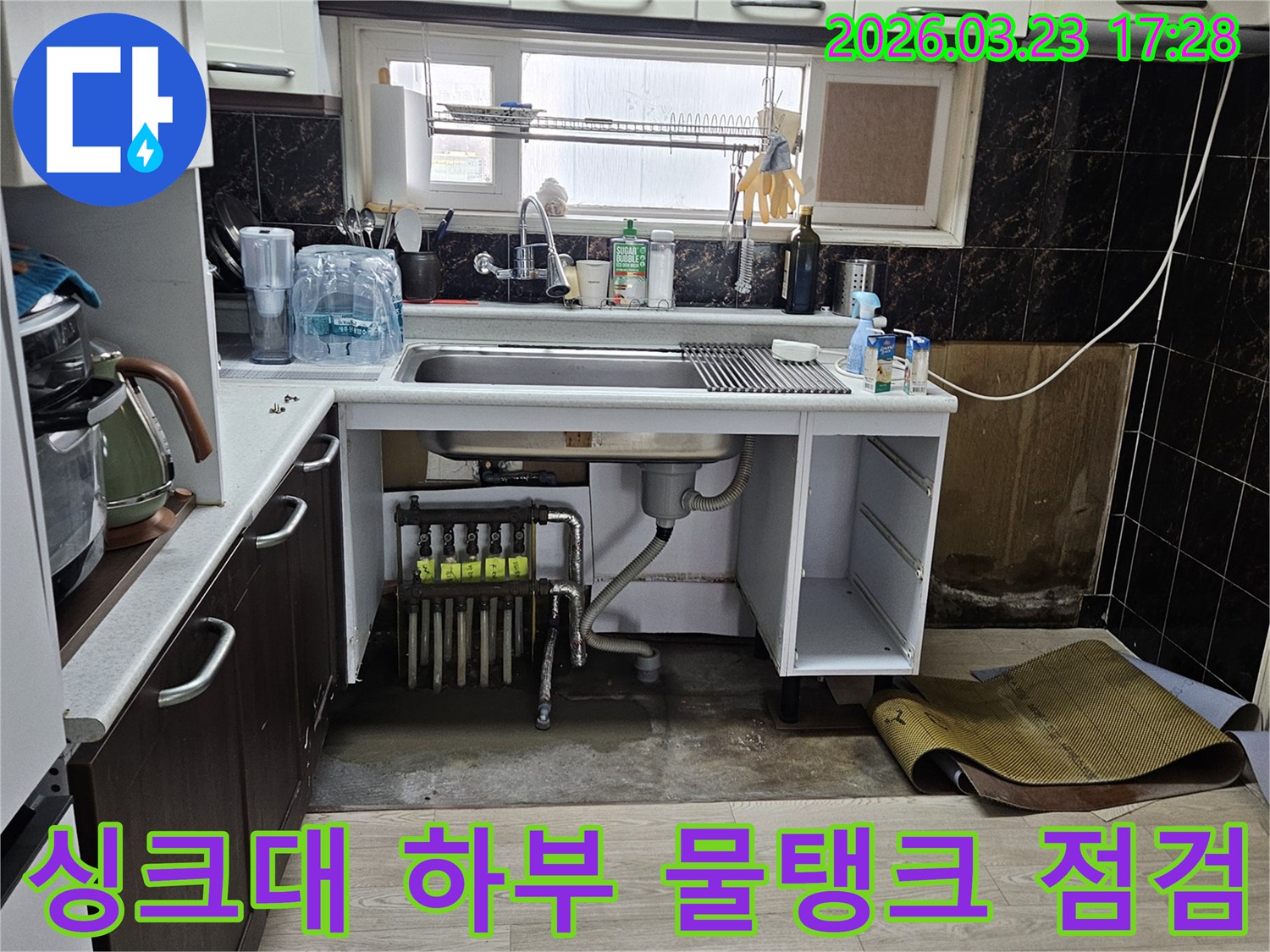 싱크대 하부의 물탱크와 연결된 배관에서-누수가 의심되어 점검하는 모습