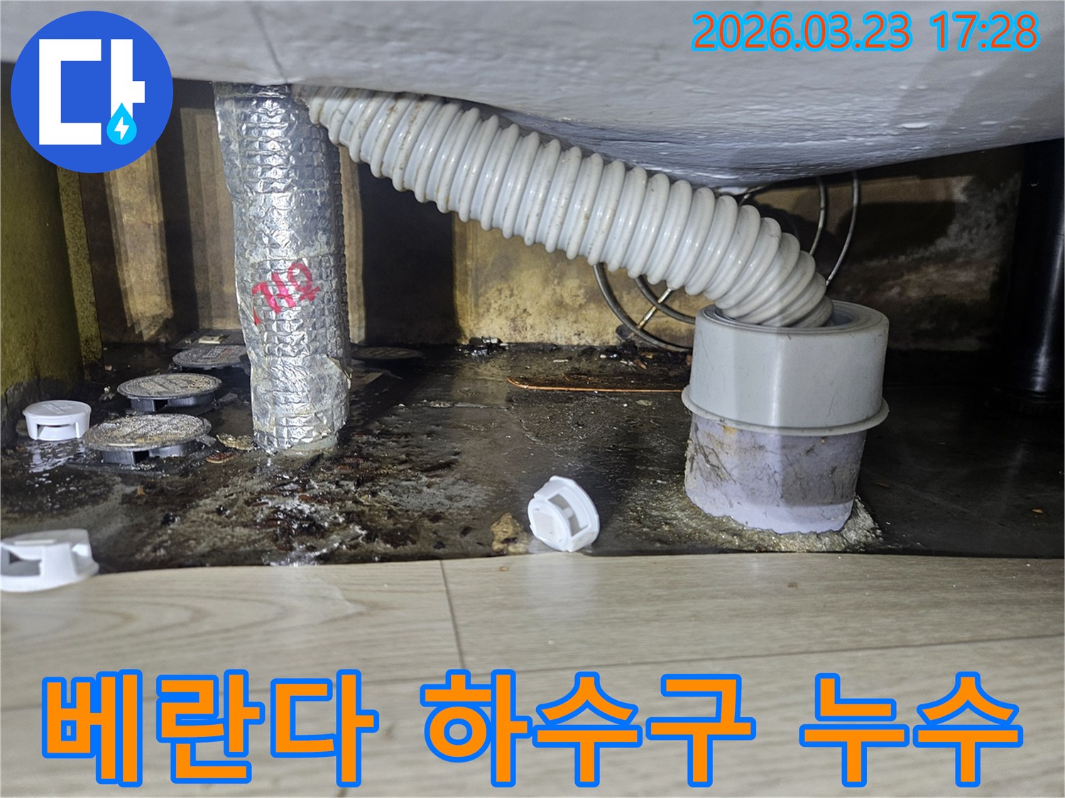 이 이미지는 베란다 하수구 주변에서 발생한 누수로 인해 바닥이 젖고 오염된 현장을 보여주며-위생적인 문제가 심각합니다.