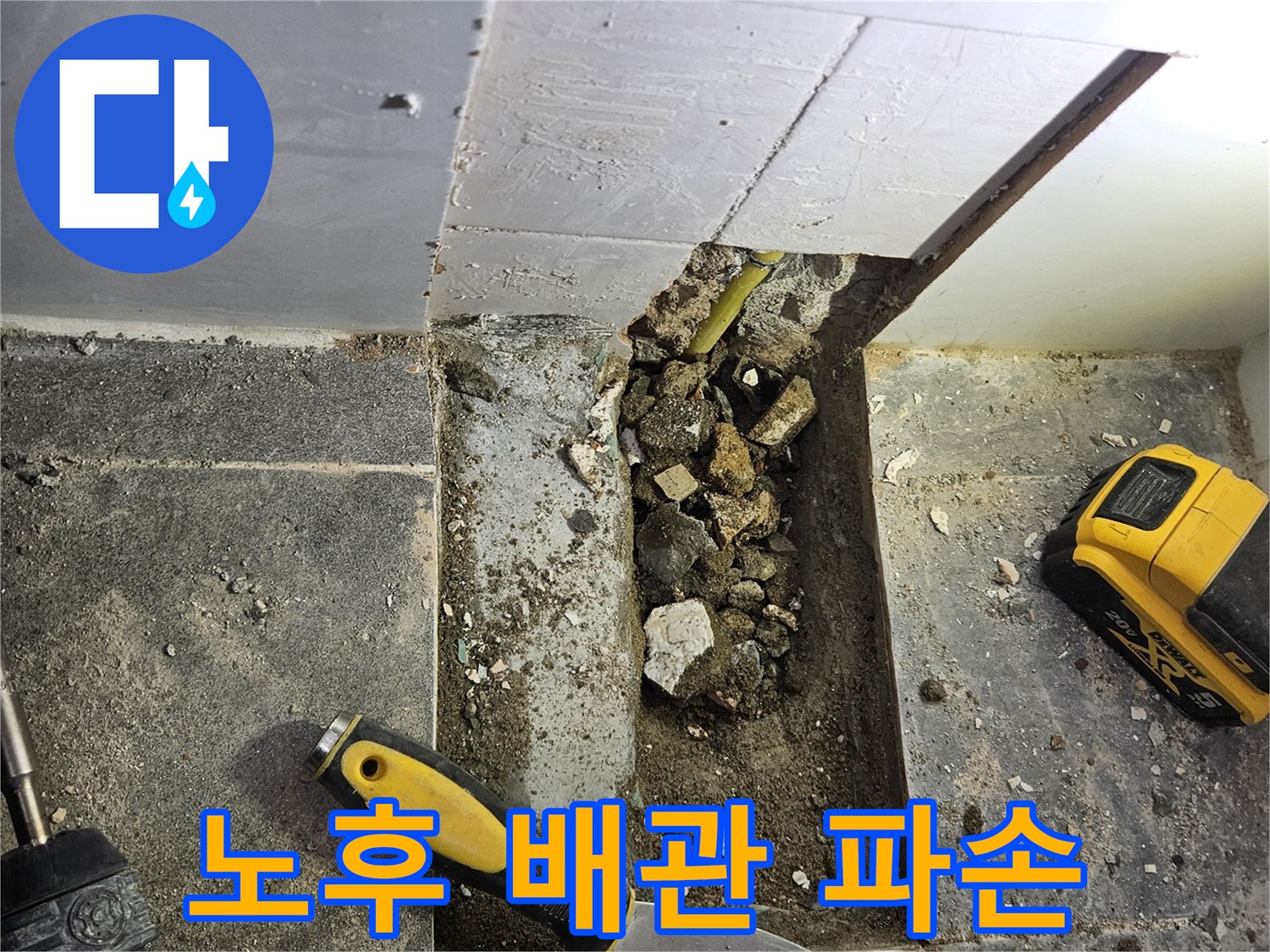 콘크리트 층 아래 노출된 손상된 수도 배관과 작업 도구들