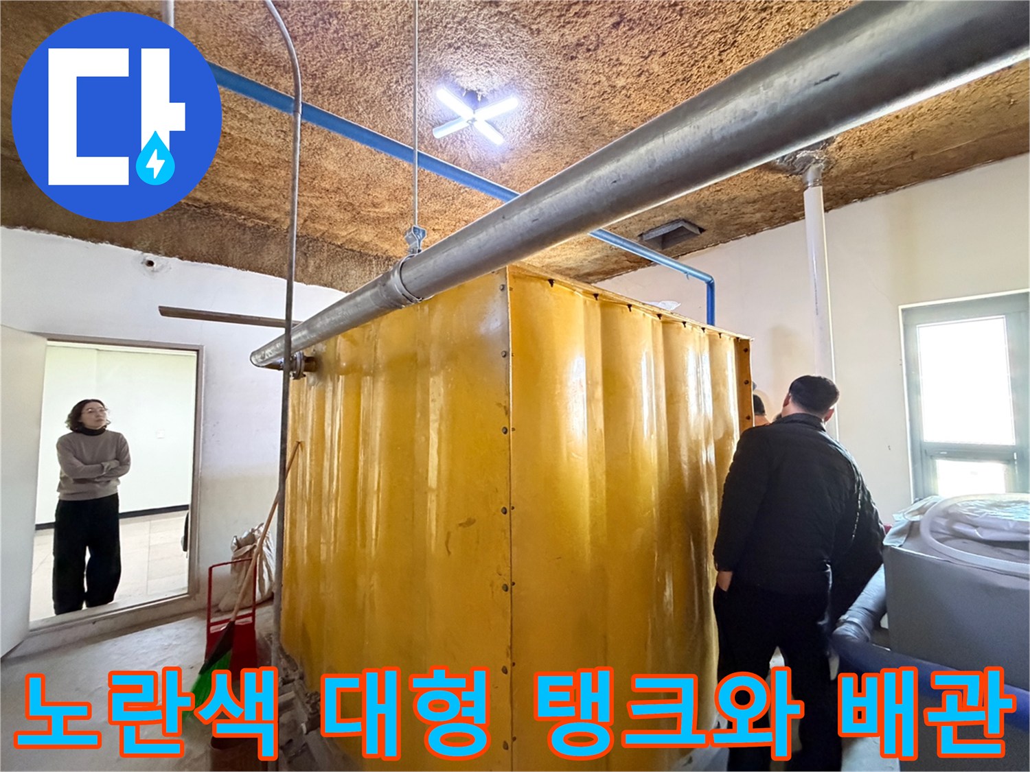 지하 시설 내부의 노란색 대형 저장 탱크와 상부 금속 배관 모습