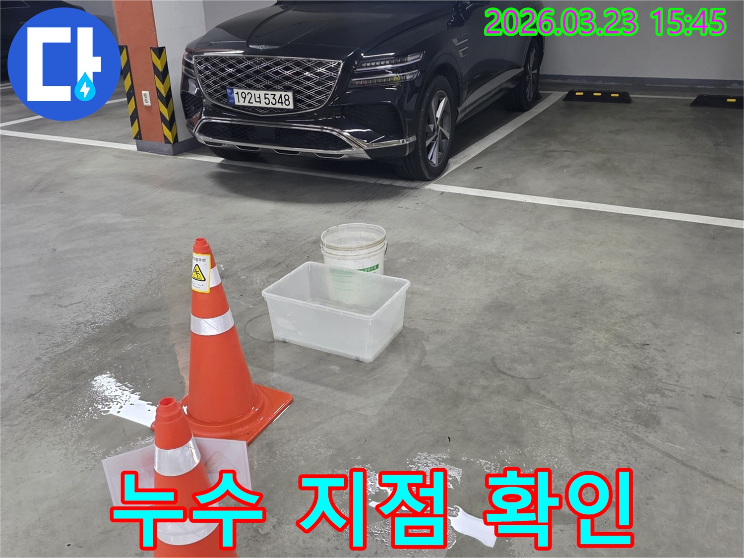 지하주차장 바닥에 물이 고여-안전 콘과 물통으로 임시 조치된-누수 현장 사진입니다.