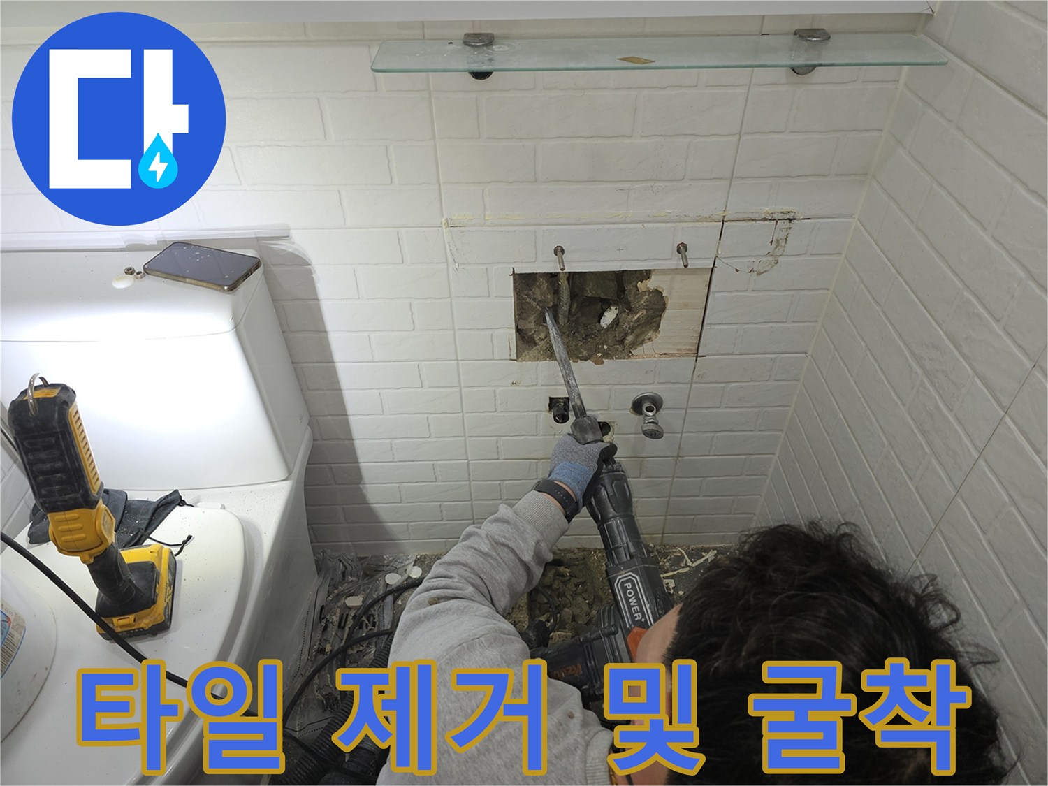누수 지점을 찾기 위해 타일을 깨고 콘크리트 벽면을 드러내는 작업자