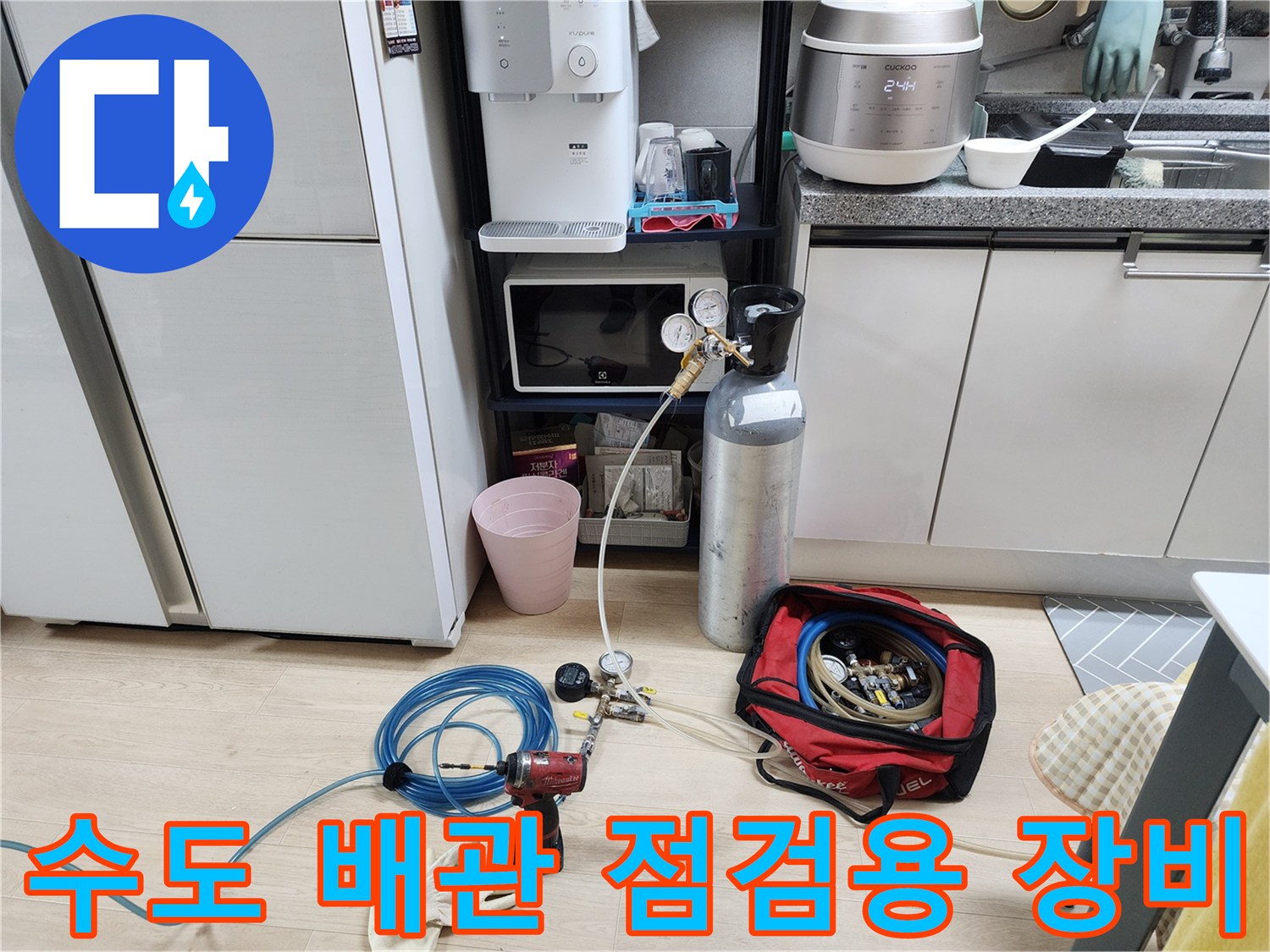 주방 하부장 근처에서 진행 중인 수도 배관 압력 테스트 장비 세팅