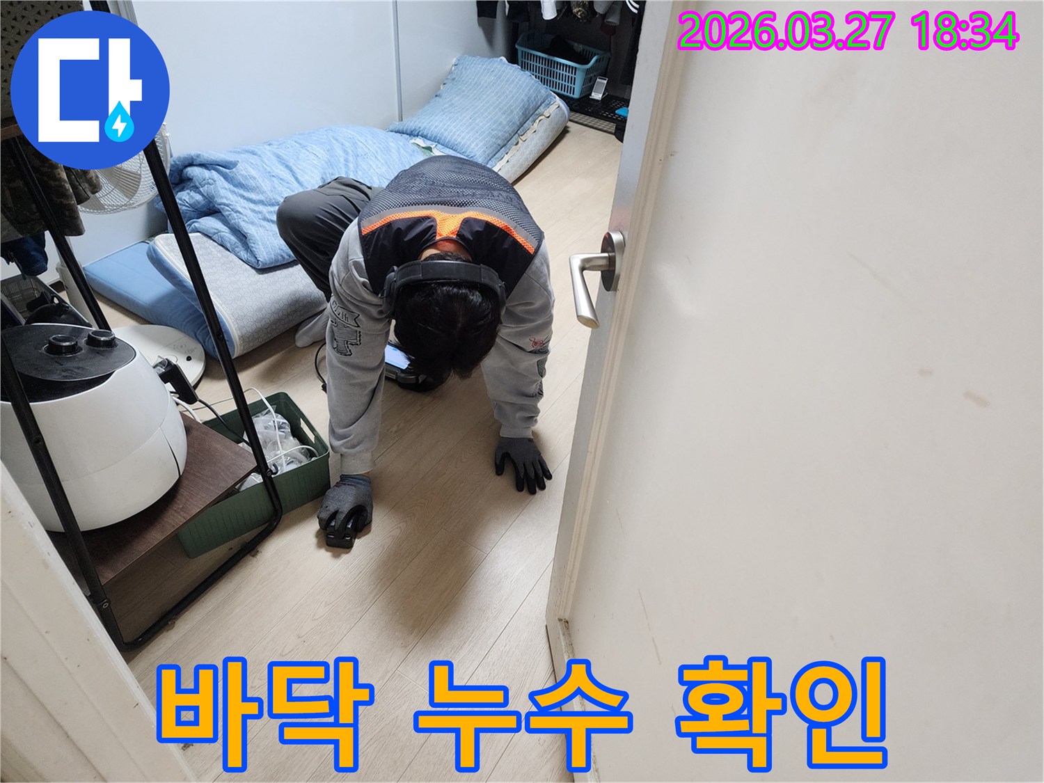 주택 내부에서 발생한-미세한 누수를 파악하기 위해-특수 장비를 착용하고-바닥면을 집중적으로 점검하는 장면입니다.