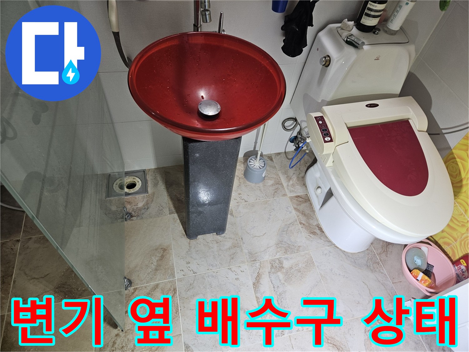 화장실 변기와 세면대 아래쪽 바닥 배수구를 촬영한 사진