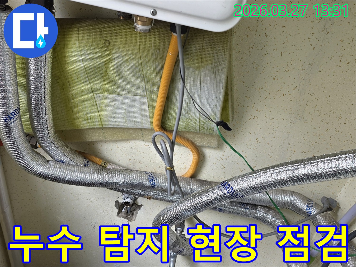 보일러-아래쪽의-복잡한-배관과-전선이-얽혀있는-모습을-보여주며-누수-탐지를-위한-초기-점검-단계입니다.