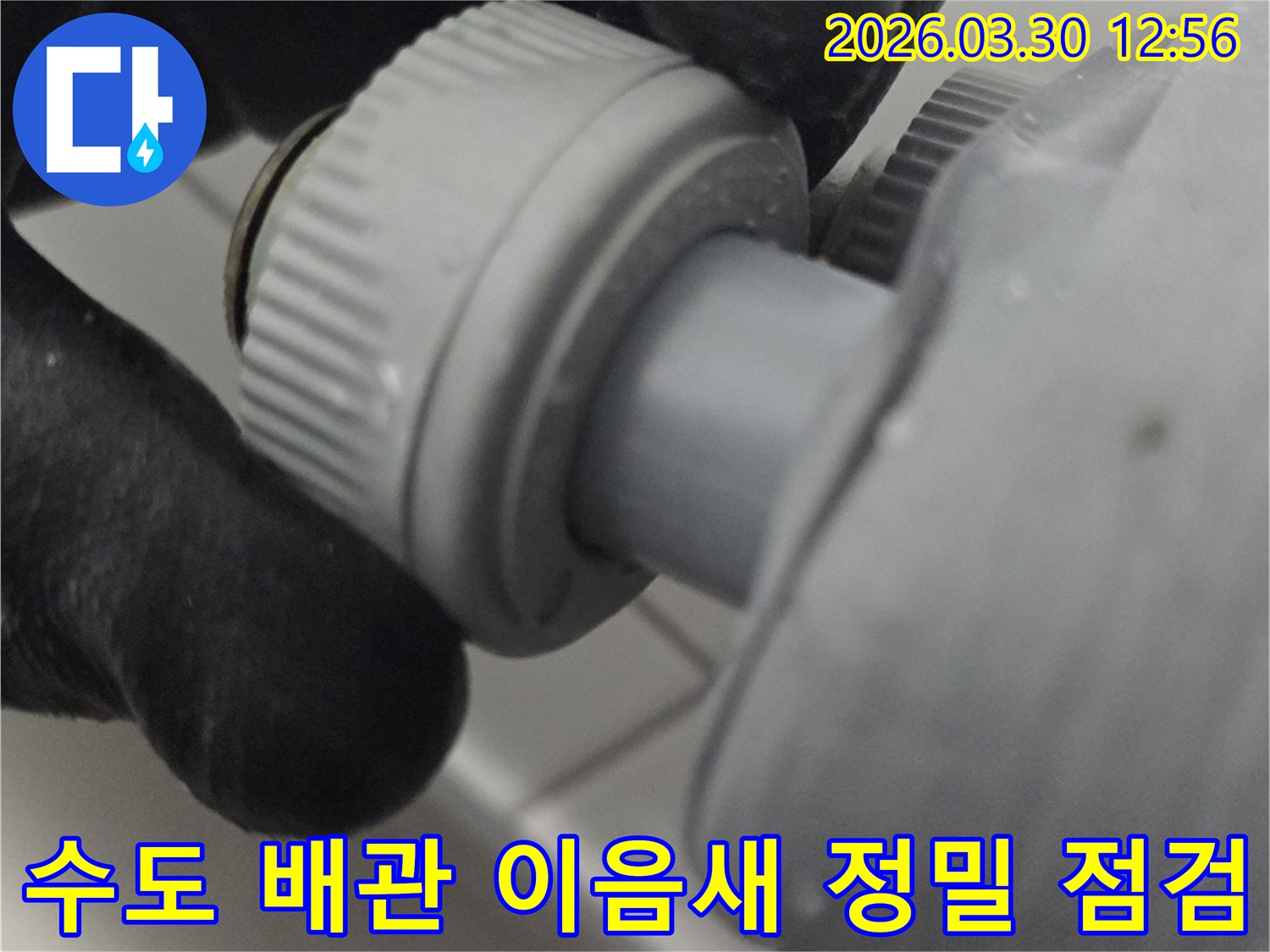누수 발생 여부를 확인하기 위해 수도 배관의 이음새 부분을 손으로 직접 만져보고 있는 전문가의 모습
