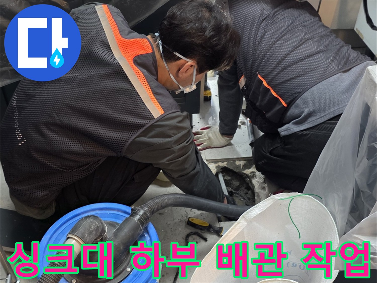 싱크대 아래 공간에서 배관 수리를 진행하는 엔지니어의 모습