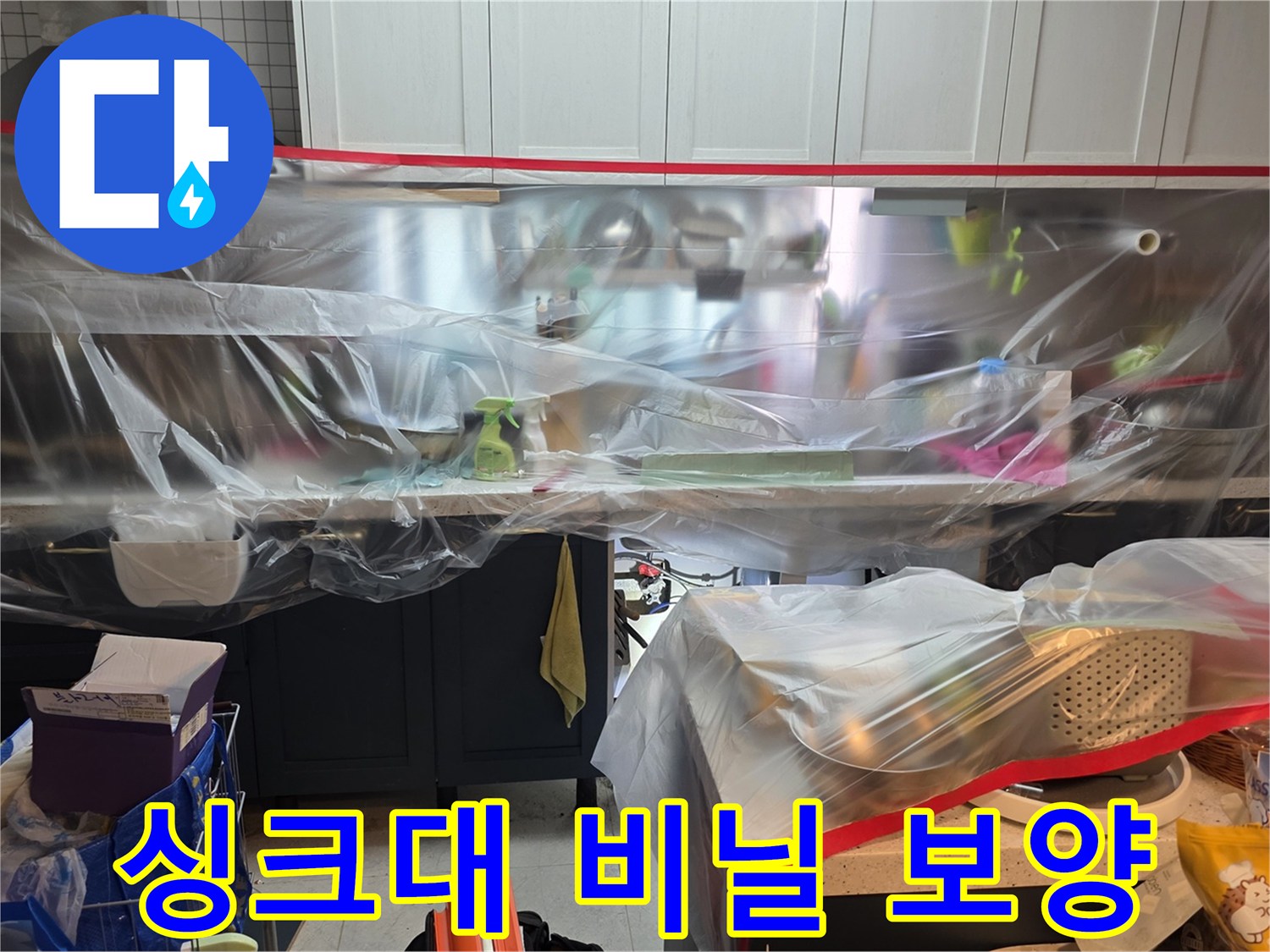 주방 싱크대 하부장 주변을 먼지로부터 보호하기 위해 투명 비닐로 꼼꼼하게 보양한 모습입니다.