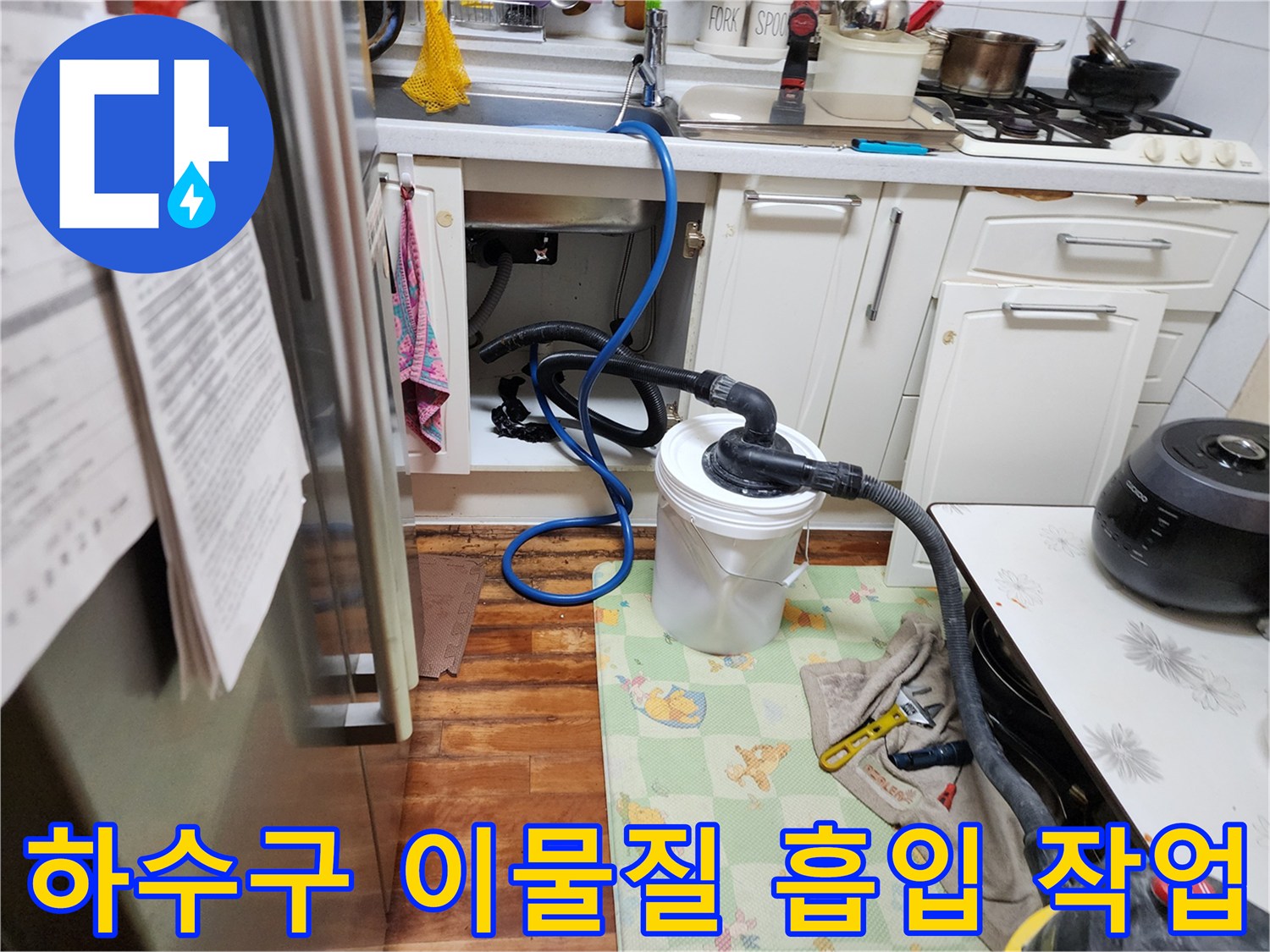 싱크대 하부 배관에 연결된 석션 호스와 오물 수거통 모습