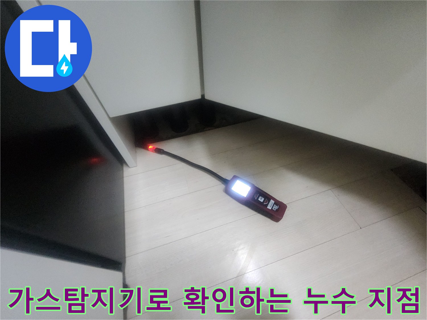 주방 싱크대 하부 공간에서 가스 탐지기를 이용해 배관의 미세한 누수를 추적하는 모습