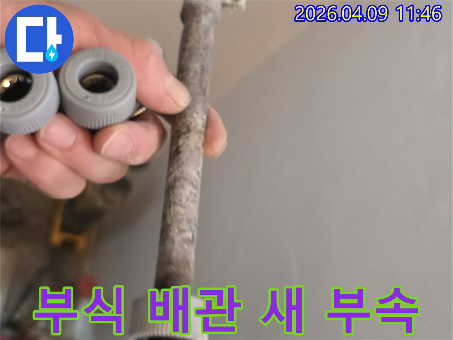 이 사진은-오랜 사용으로 부식된 수도관과-새롭게 교체할 배관 부품을-함께 보여주고 있습니다