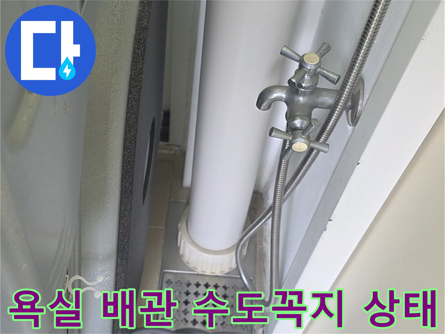 화장실 벽면에 설치된 은색 수도꼭지와 연결된 배관 모습