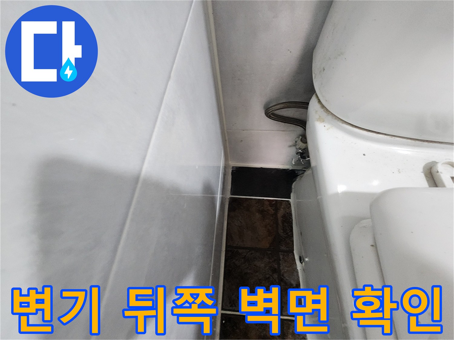변기 옆 타일과 급수 호스 연결 부위 근접 촬영
