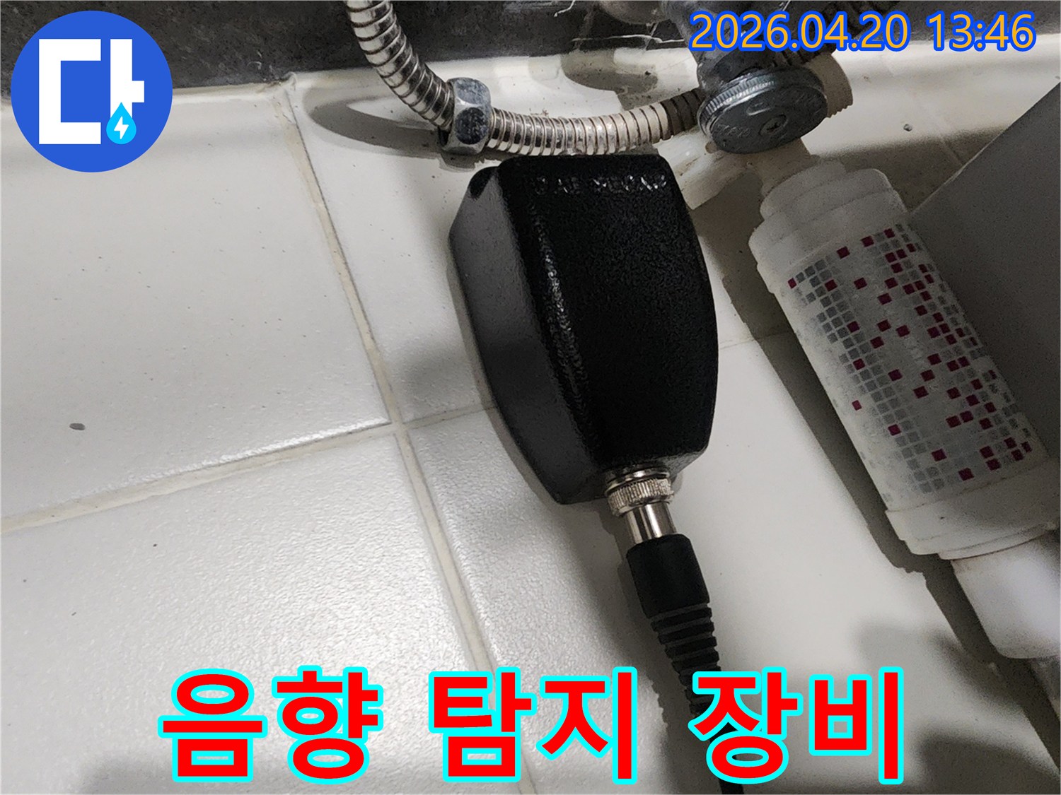 누수 탐지 전문가가-주택 욕실 바닥에서-배관 누수음을 감지하기 위해-음향 탐지 장비를 설치한 모습입니다.