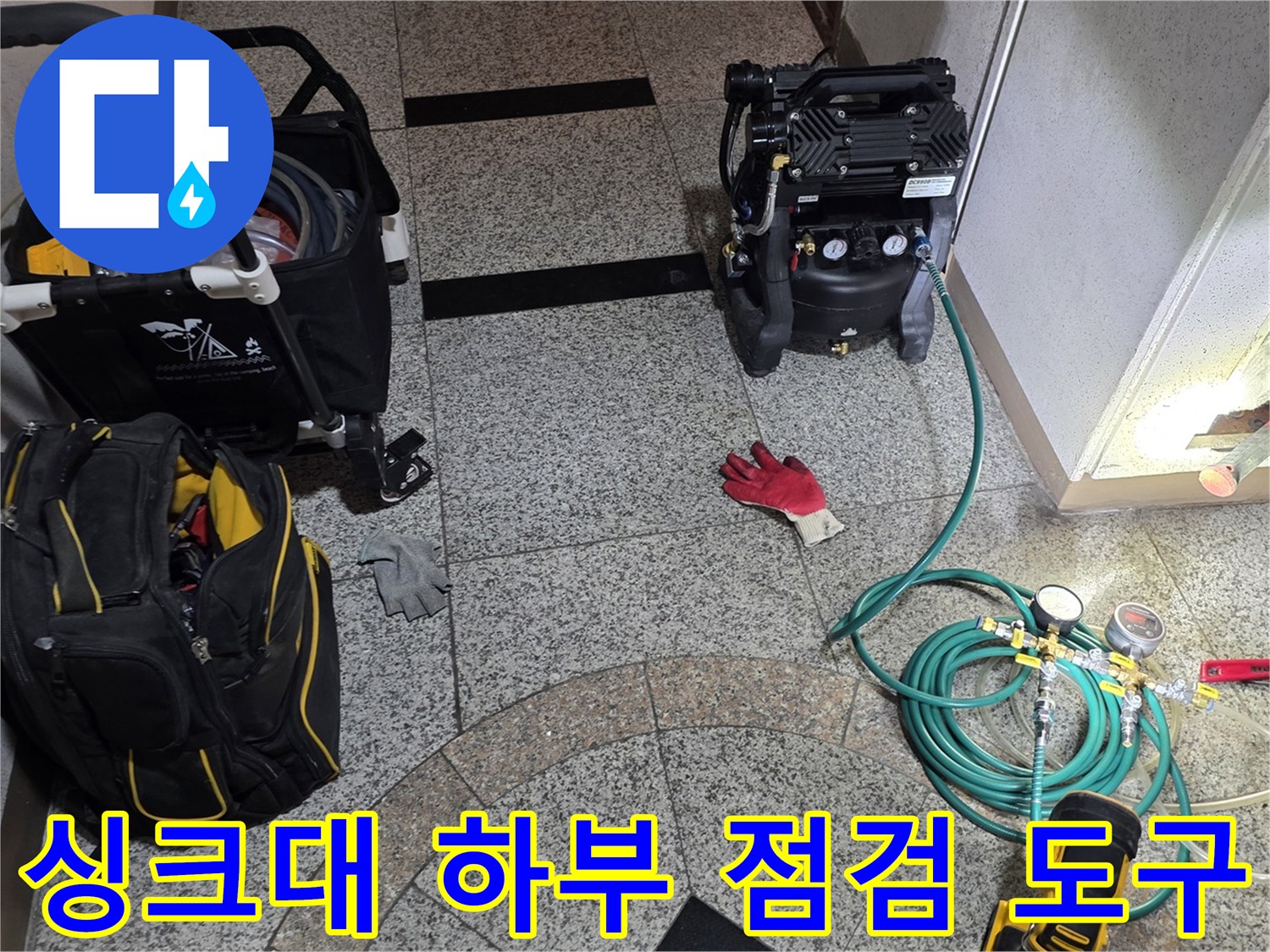 싱크대 바닥 타일 위에 세팅된 누수 탐지용 공압기와 호스들