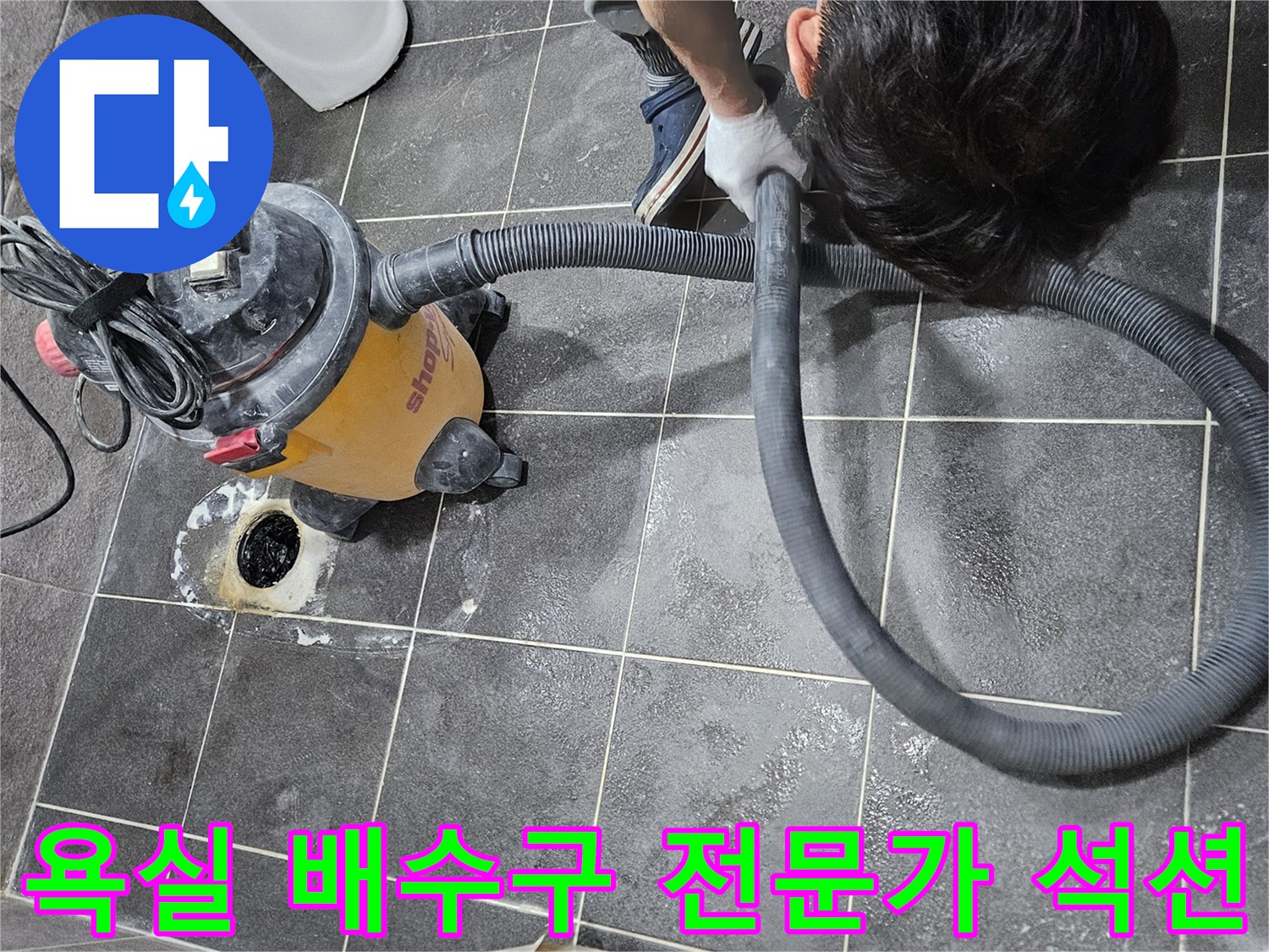 아파트 욕실 배수구의 이물질을-전문가가 강력한 석션 장비로-깨끗하게 청소하는 작업 현장