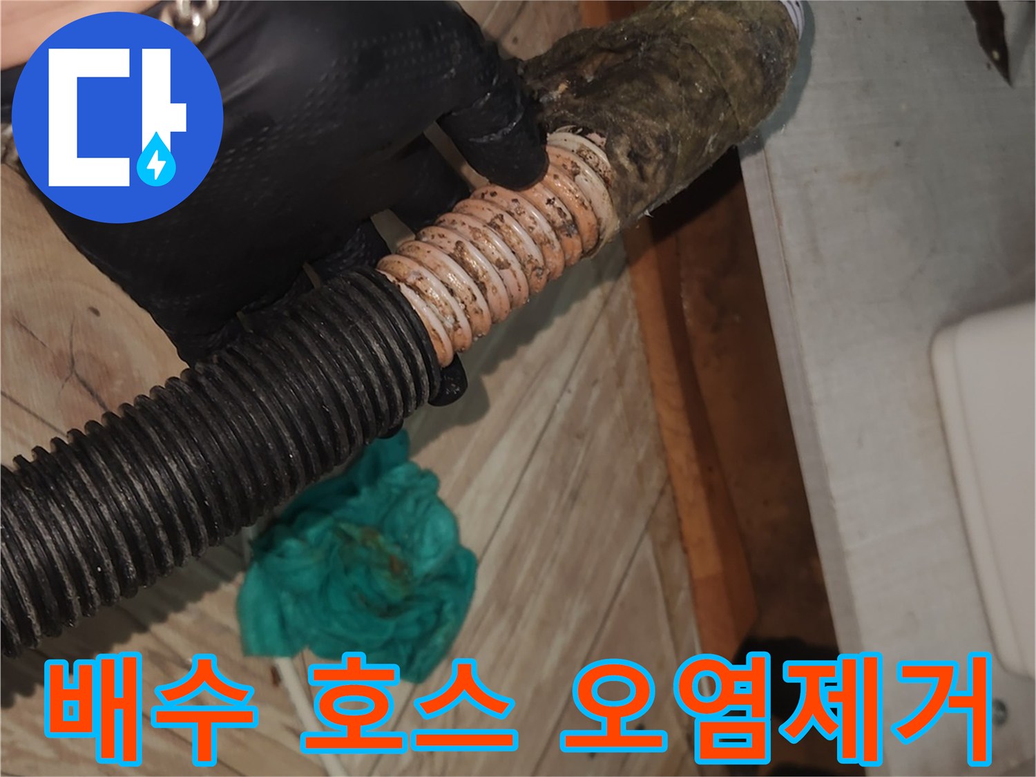 검은색 작업 장갑을 낀 손이-오래된 싱크대 배수 호스를-꼼꼼하게 점검하며-클리닝 작업을 준비하는 현장 사진