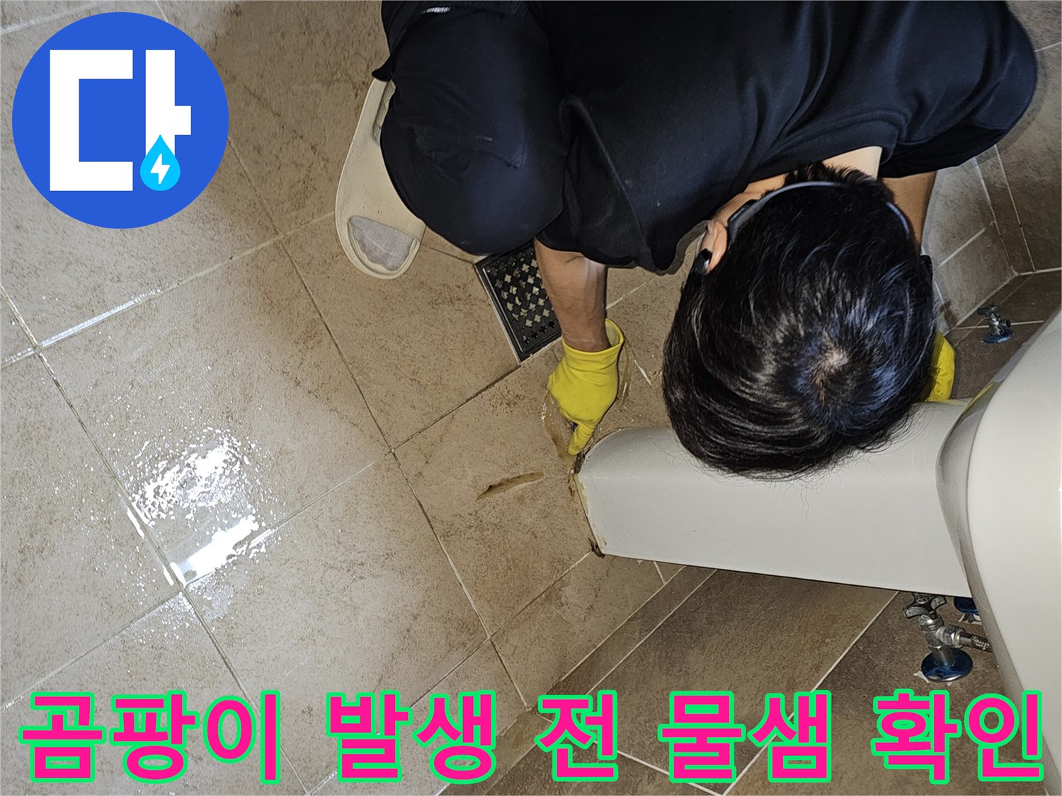 전문 엔지니어가-노란 장갑을 끼고-욕실 바닥의 젖은 타일과-세면대 하단부를-집중적으로 관찰하며-곰팡이 발생 전 물샘을 확인합니다