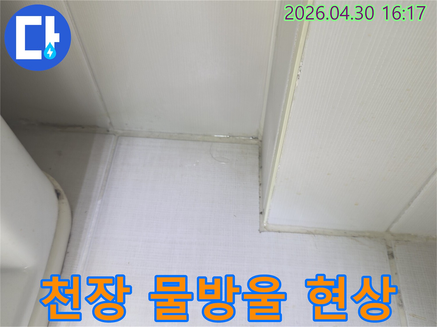 천장과 벽의 접합부에서 물방울이 맺히고-벽지가 젖어있는 상태를 보여주는-누수 발생 현장의 클로즈업 이미지