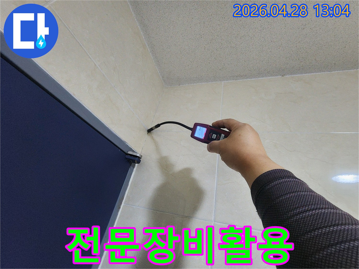 숙련된 누수 전문가가-첨단 장비를 활용하여-욕실 벽면과 바닥 경계의-미세한 누수 흔적을-꼼꼼히 확인하고 있습니다