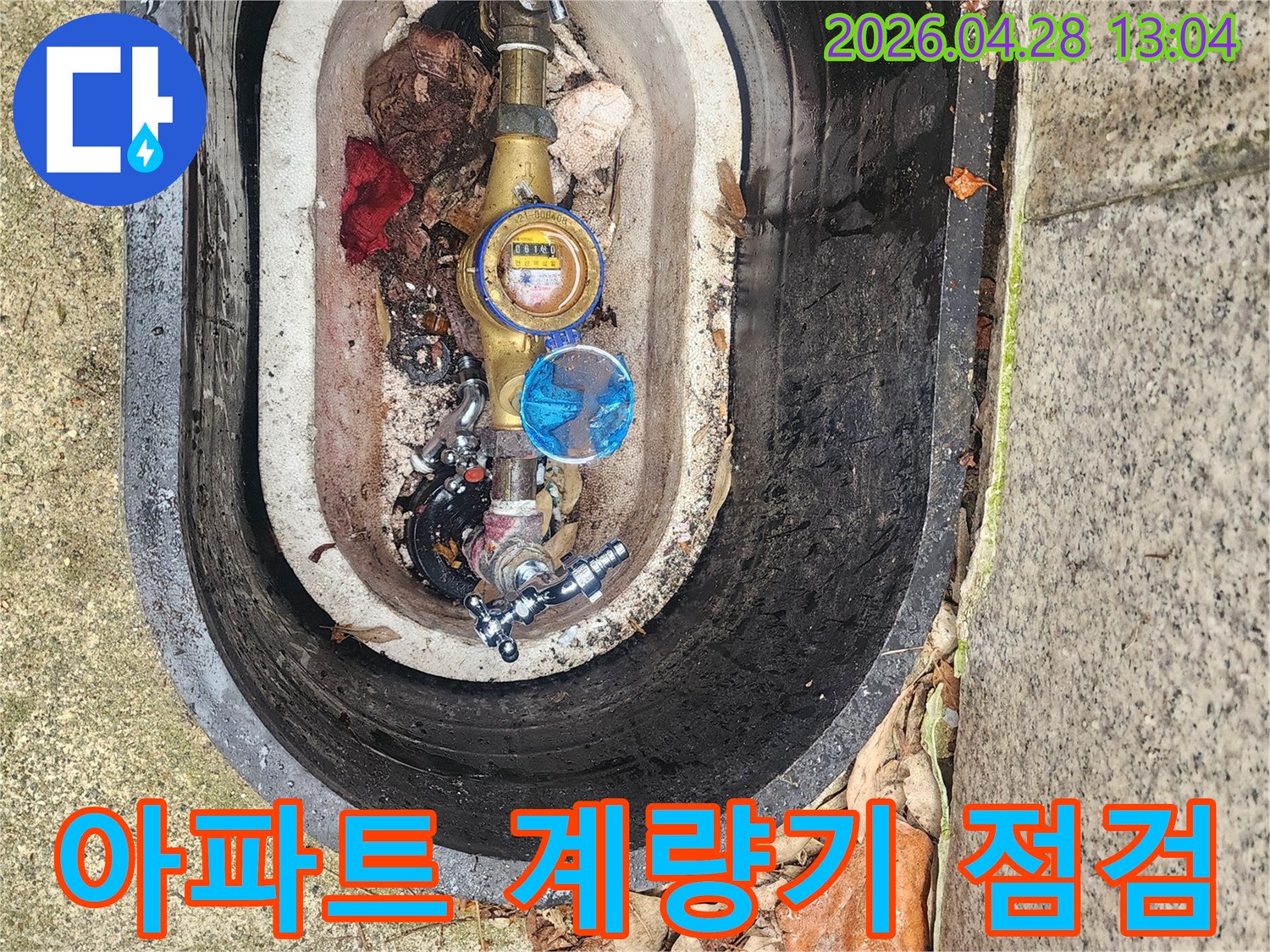 아파트 단지 내 수도계량기함 내부의 배관 상태를 점검하며-누수 발생 여부를 확인하고 있습니다.