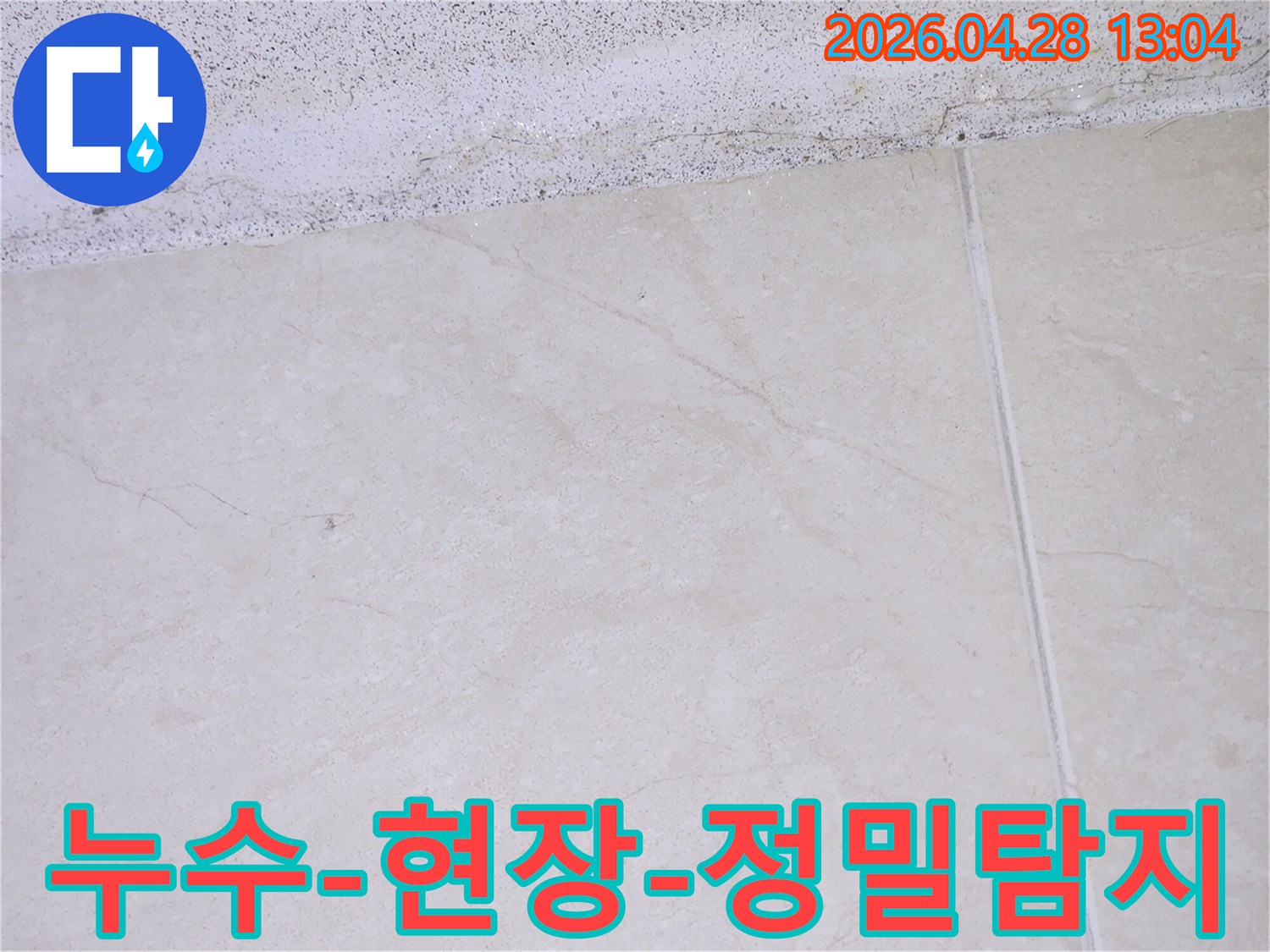 이 이미지는 천장과 바닥 타일의 접합부에서 발견된 누수-의심 흔적을 보여주며- 전문 누수-엔지니어가 현장을 정밀하게 탐지하고 있습니다.