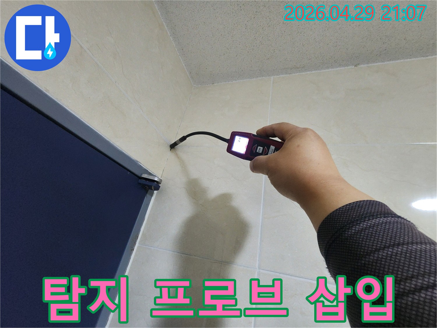 누수 전문가가-정밀 탐지 장비의 프로브를-벽면 틈새에 삽입하여-누수 원인을 분석하고 있습니다.