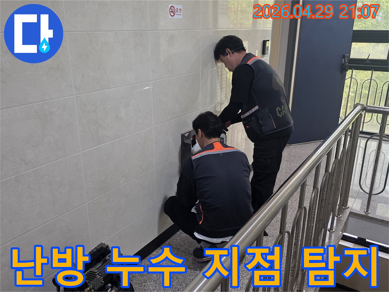 두 명의 전문 기술자가 건물 벽면 내부의 난방 누수 의심 지점을 정밀하게 탐지하고 있습니다-난방 효율 개선과 쾌적한 실내 환경을 위한 필수 작업입니다.