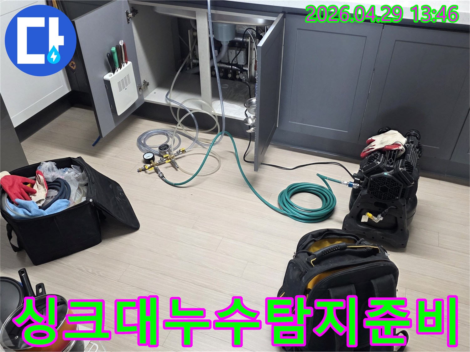 싱크대 하부장 내부에서-누수 탐지를 위해-배관에 압력 게이지를 연결하고-장비를 설치하는 모습입니다