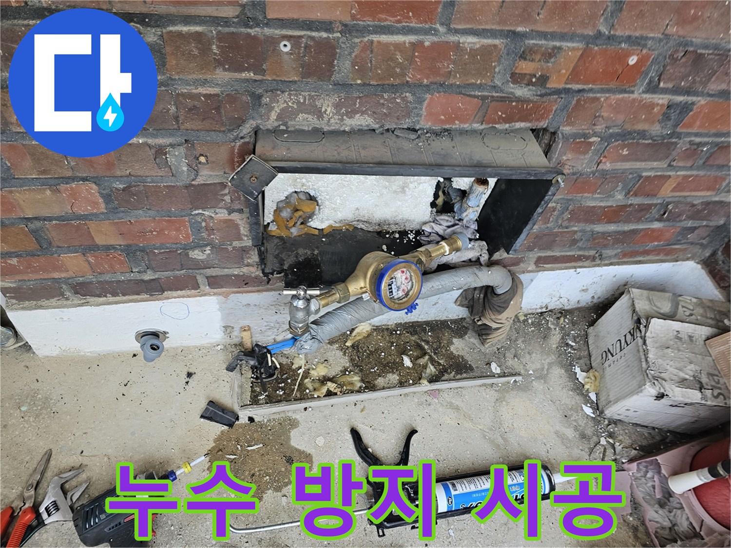 누수 공사 중 수도 계량기와 연결된 배관을 점검하고 보수하는 작업 현장입니다