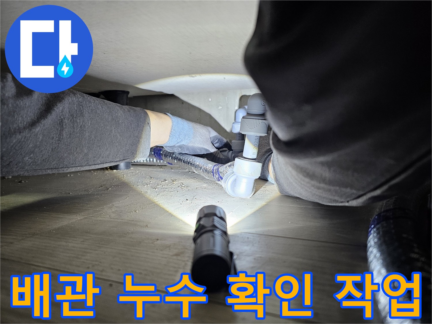 숙련된-기술자가-좁은-공간에서-손전등을-사용하여-배관-누수-여부를-확인하는-장면