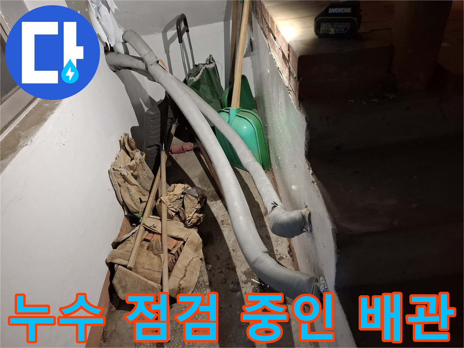 벽면을 따라 설치된 회색 배관과 작업용 삽