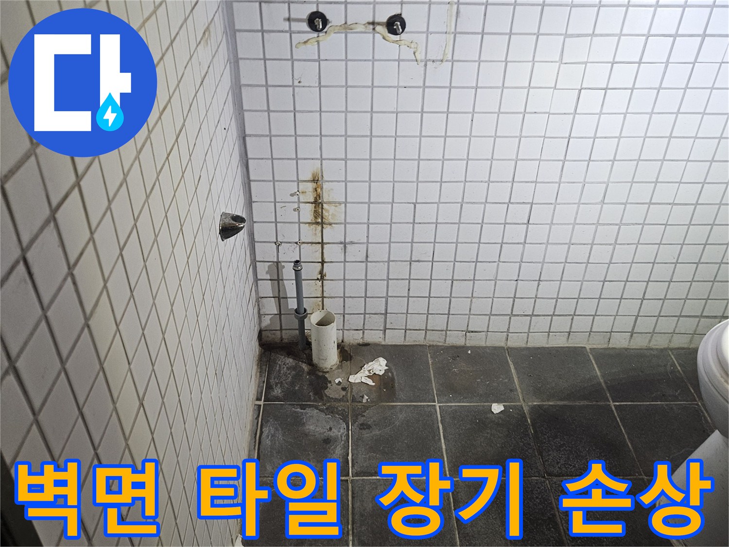 세면대 제거 후-욕실 검은색 타일 벽면에-노출된 하수 배관 주변의-장기적인 물 노출로 인한-타일 손상 상태를-꼼꼼히 확인하는-누수 전문가