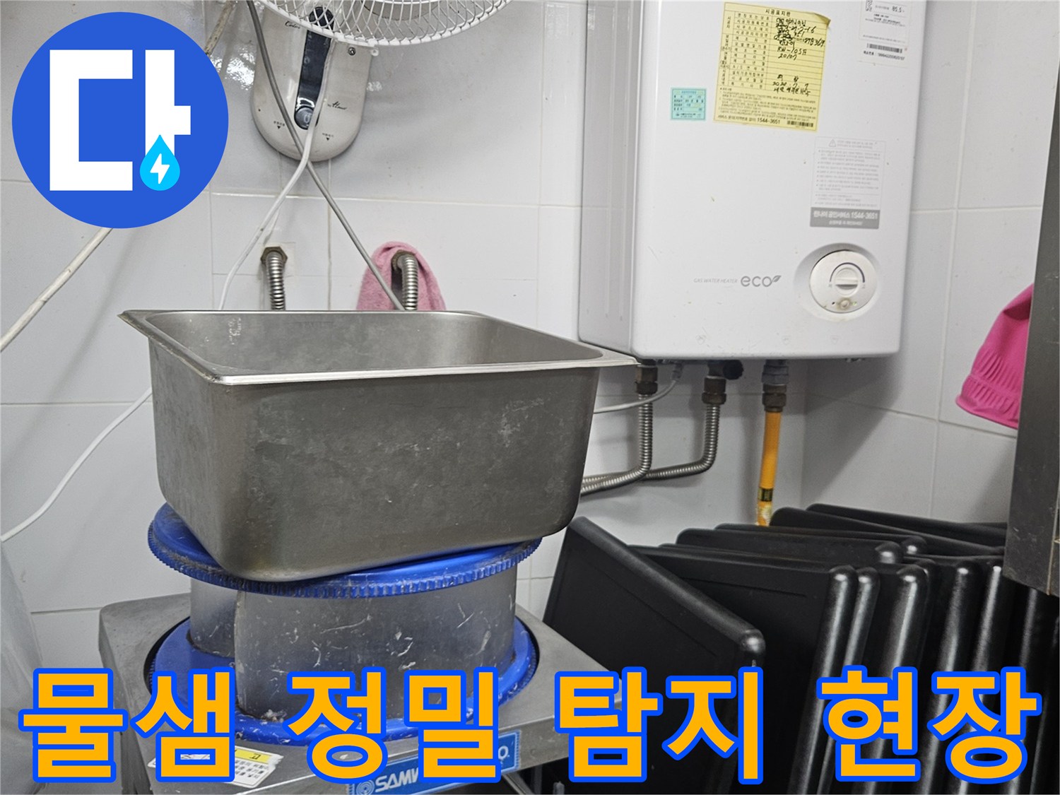 이 이미지는 보일러와 싱크대-그리고 다양한 배관이 있는 공간에서-물샘 현상의 원인을 찾기 위해 정밀 탐지 작업을 수행하는 모습을 담고 있습니다.