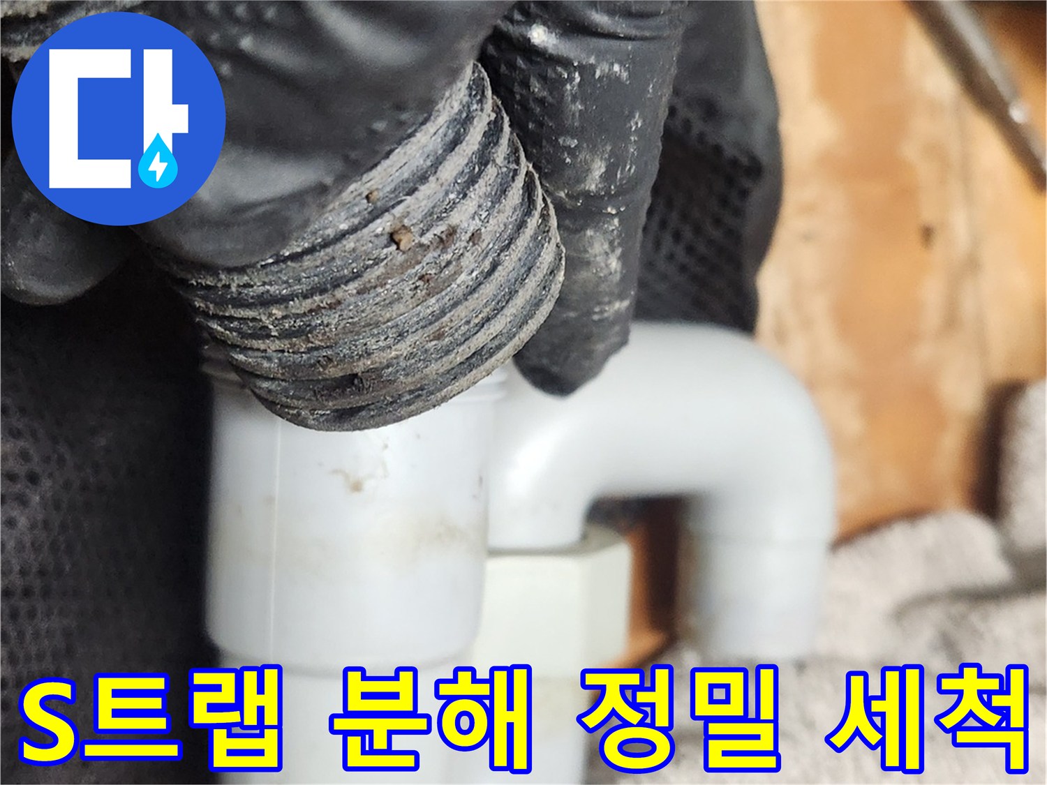 작업자가 검은 장갑을 착용하고-S트랩 배관을 완전히 분해하여-내부 구조를 확인하고 있습니다