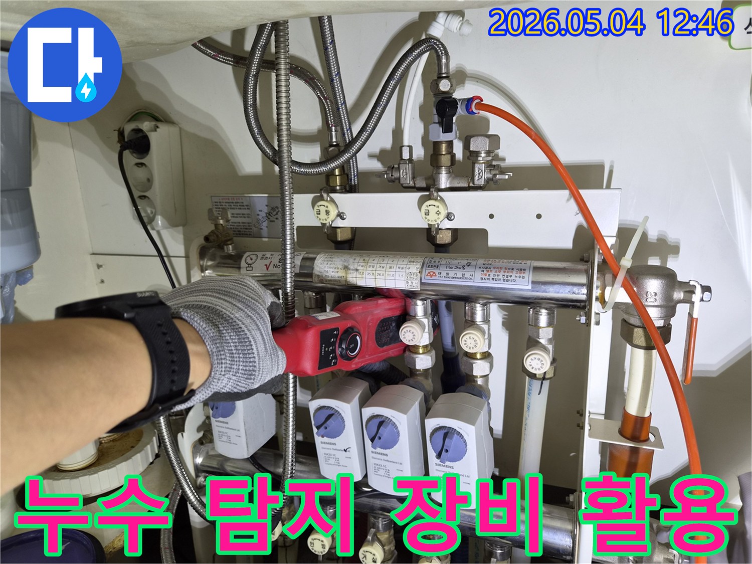 누수-탐지-전문가가-첨단-장비를-사용하여-배관-분배기-주변을-정밀하게-검사하는-장면