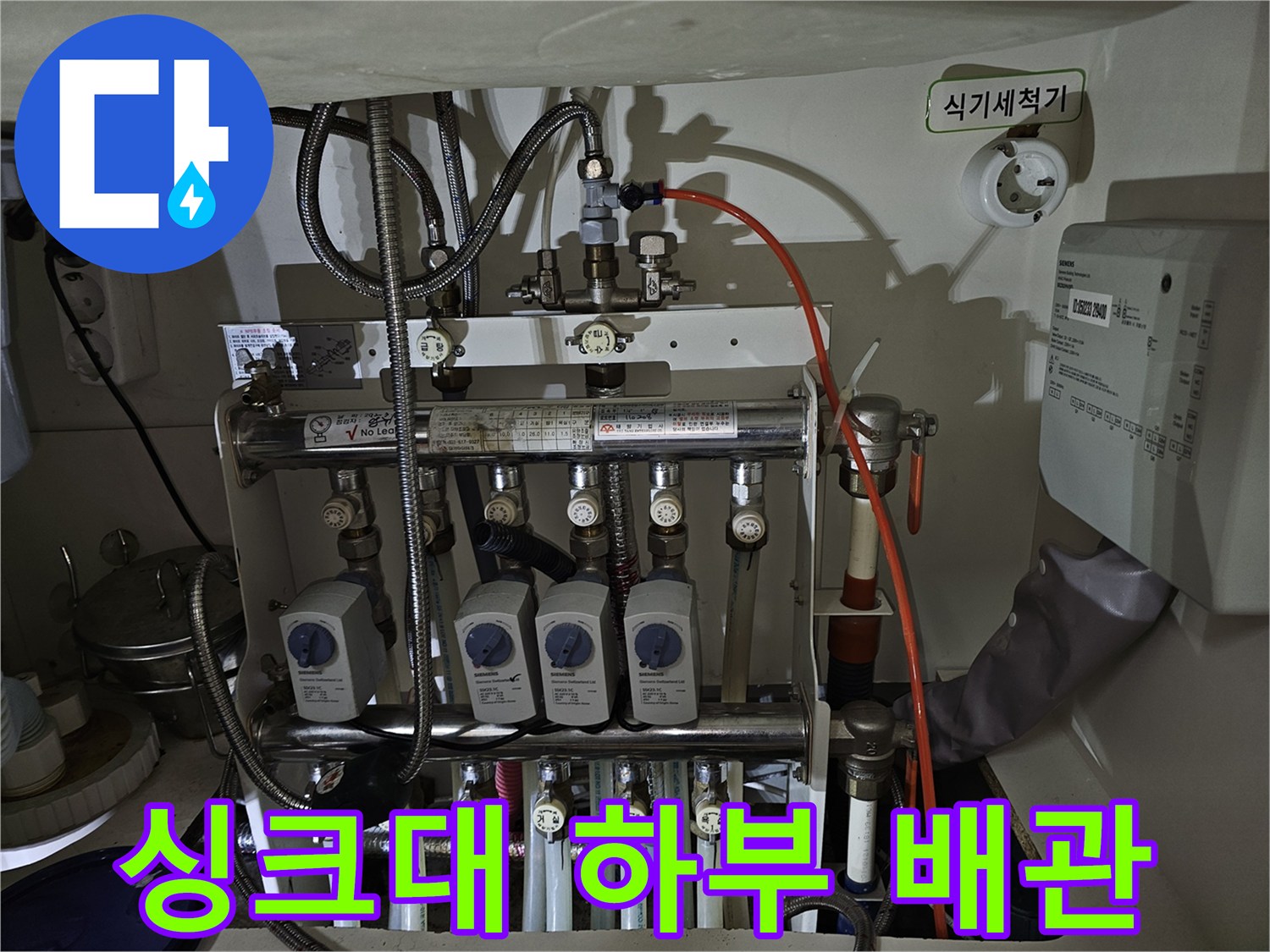 복잡한 구조의 분배기와 밸브들이 설치된 주방 하부 배관 내부 모습
