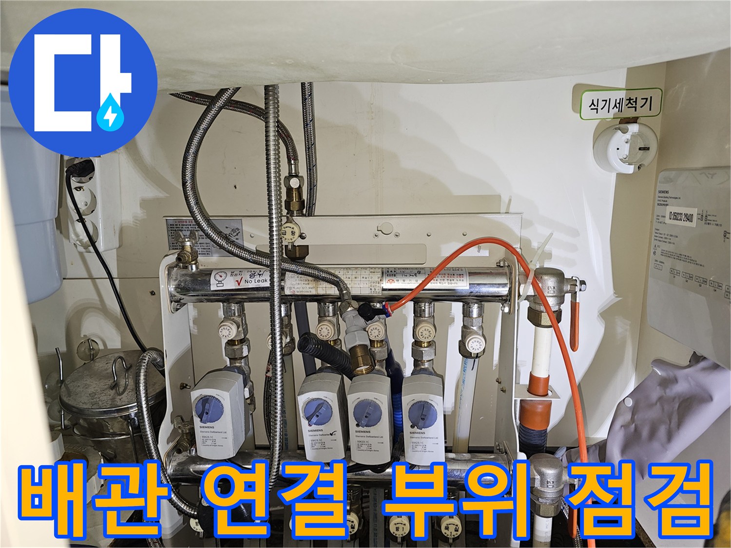 싱크대 아래 분배기 밸브와 연결된 금속 및 플라스틱 배관들