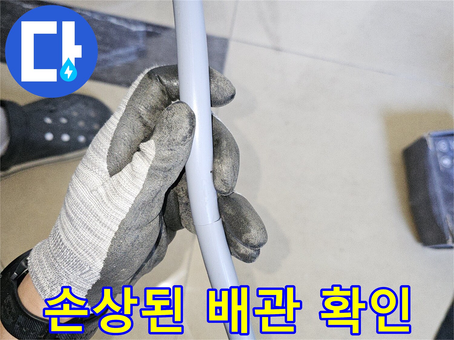 작업용 장갑을 낀 손으로 회색 배관의 결함을 점검함