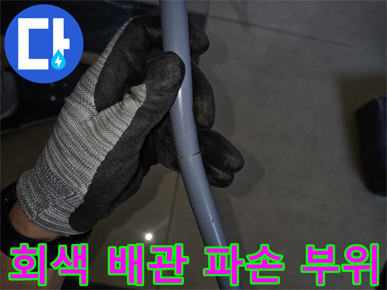 작업자가 손으로 잡고 있는 회색 배관의 균열된 연결 부위
