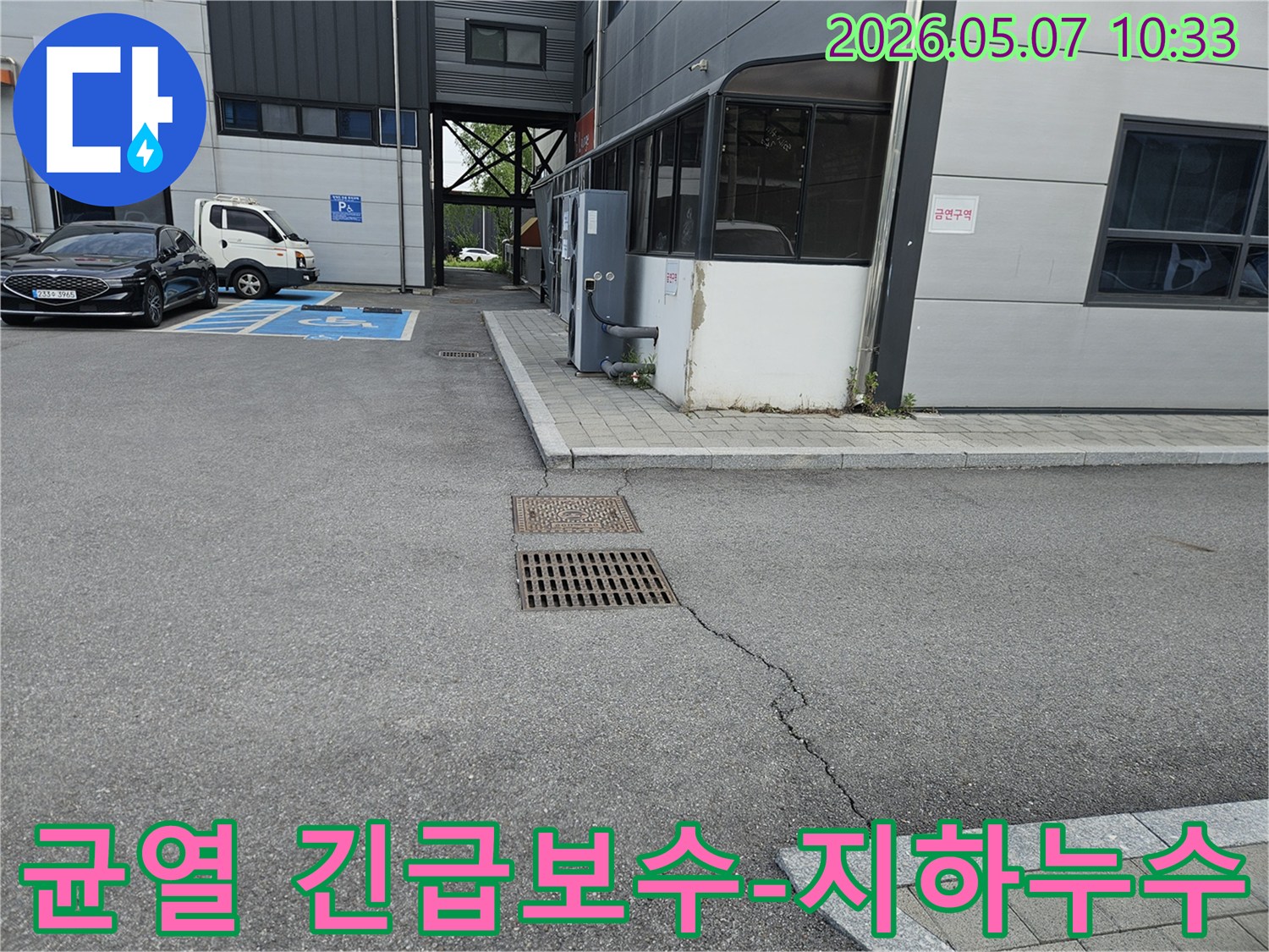 이 이미지는 의정부시 만가대길 주차장의 아스팔트 균열과-맨홀-배수구 주변의 지반 문제를 보여주며-지하 누수로 인한 긴급 보수가 필요한 현장입니다.