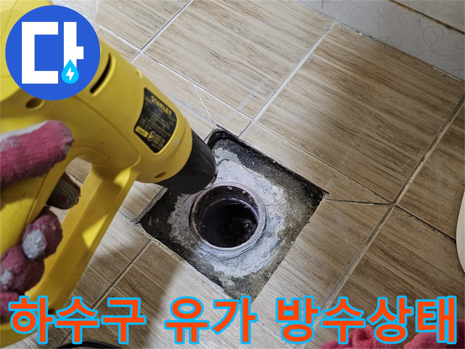 욕실 배수구 주변의 파손된 타일과 하수관 노출 사진