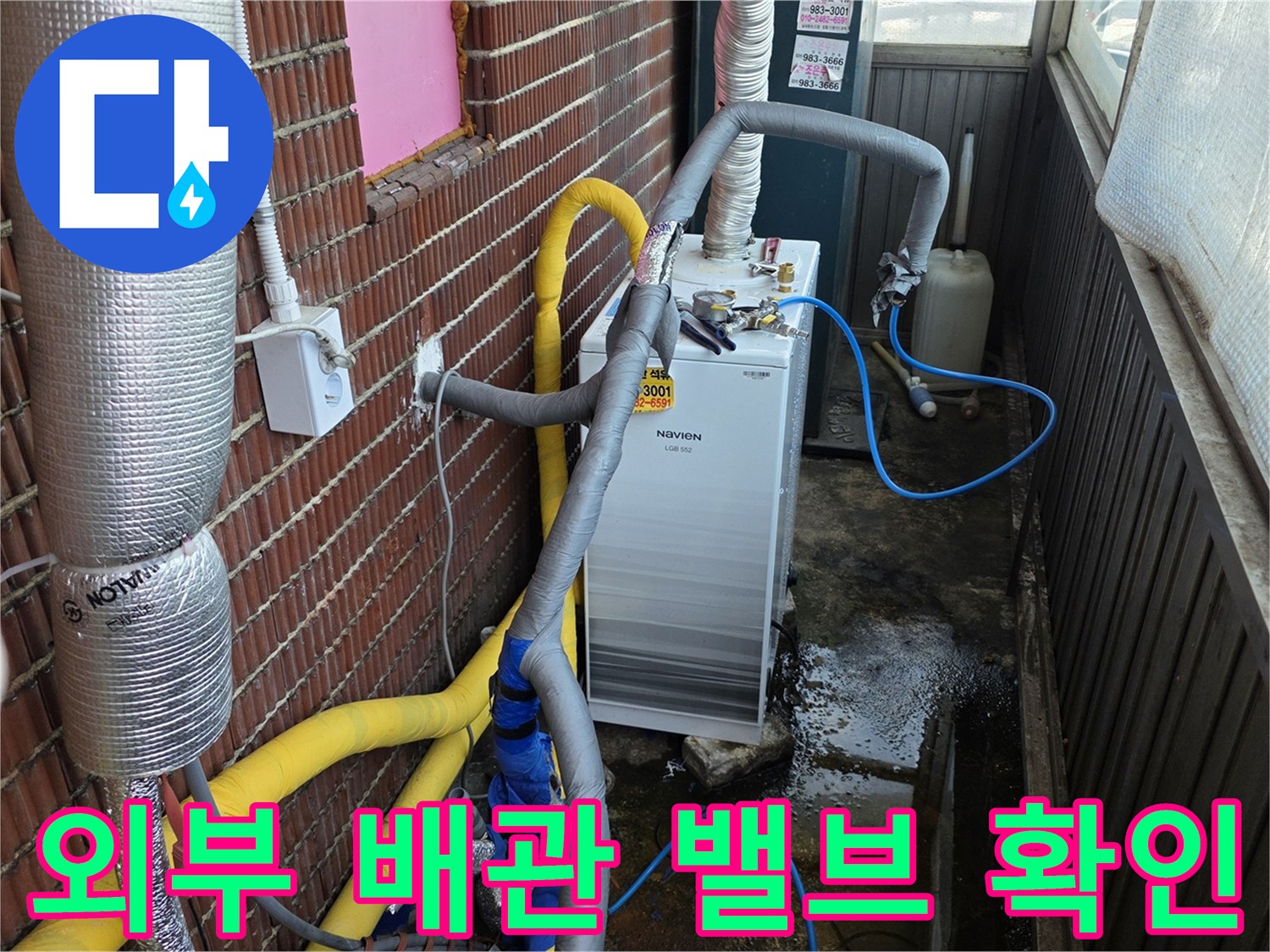 벽돌 벽면에 연결된 흰색 장비와 외부 배관의 상세 모습