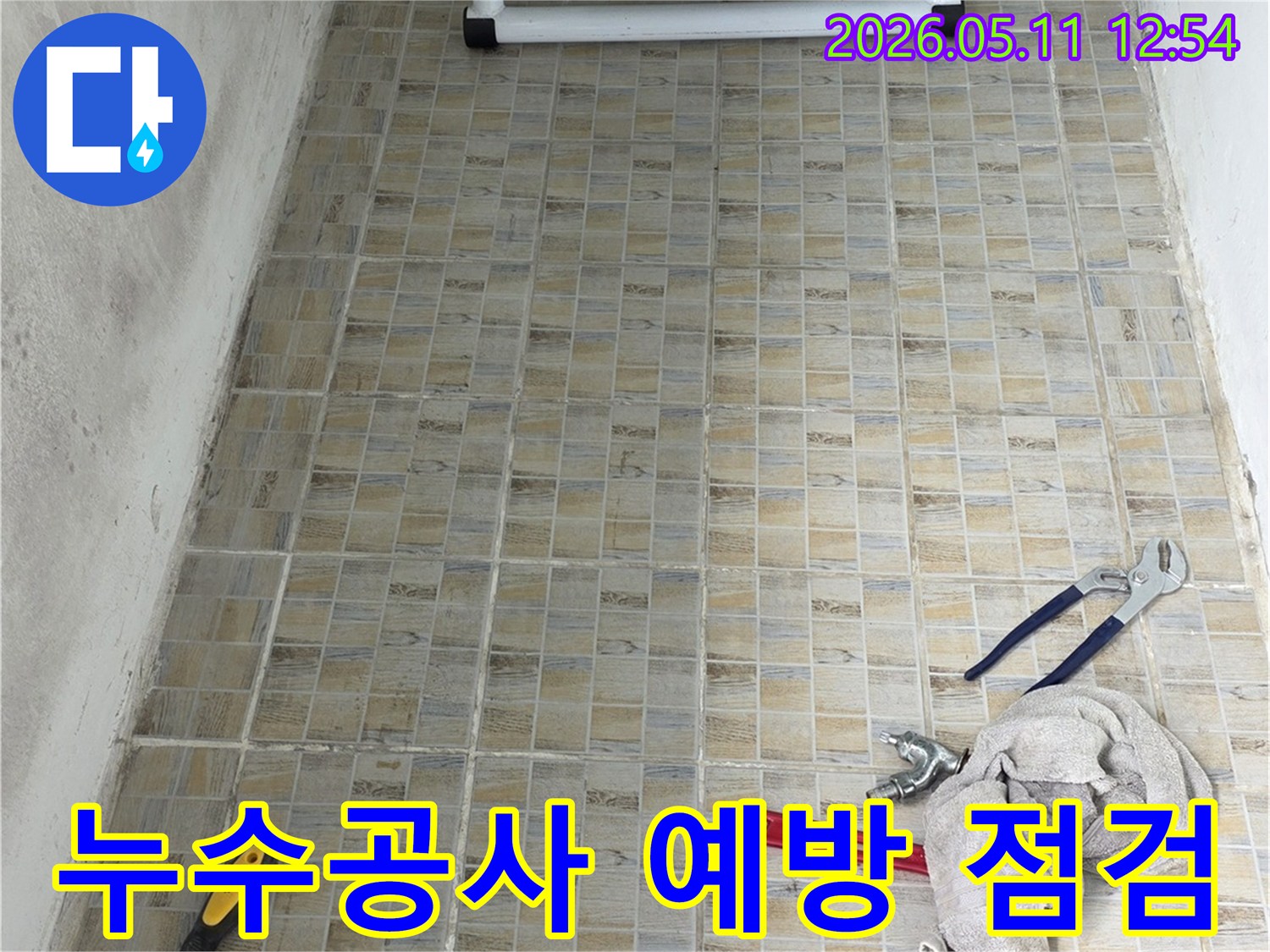 누수 공사 현장에서-타일 벽면과-작업에 필요한 공구들이 놓여있는 모습