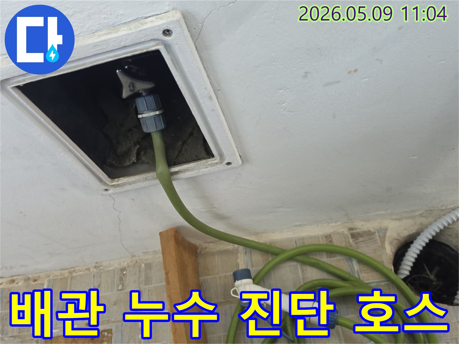 천장 점검구를 통해 배관 누수 진단을 위한 호스를 삽입하여 내부를 검사하는 장면