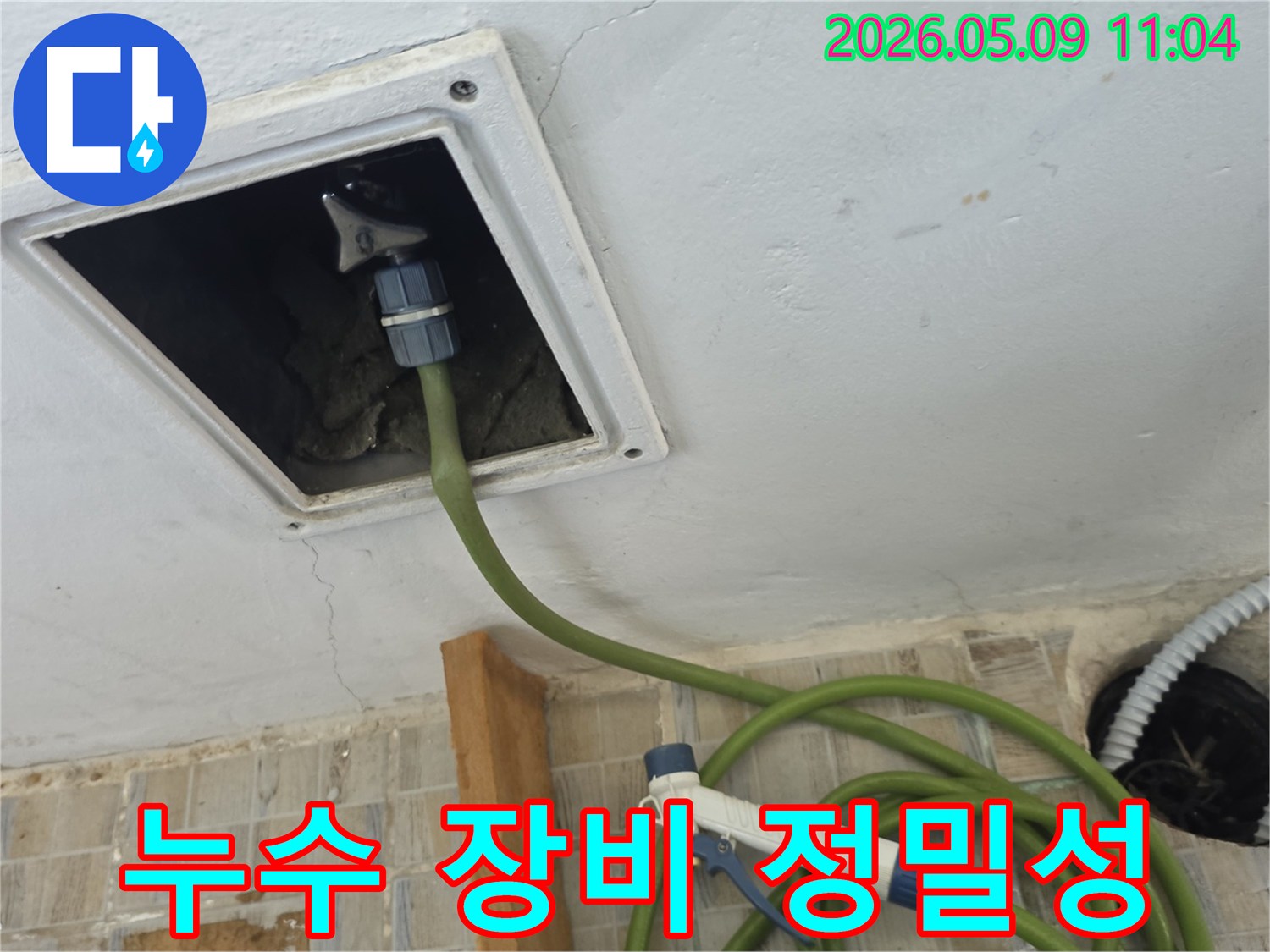 천장 점검구에 누수 탐지 장비 호스를 연결하여 누수 지점을 정밀하게 찾아내는 모습