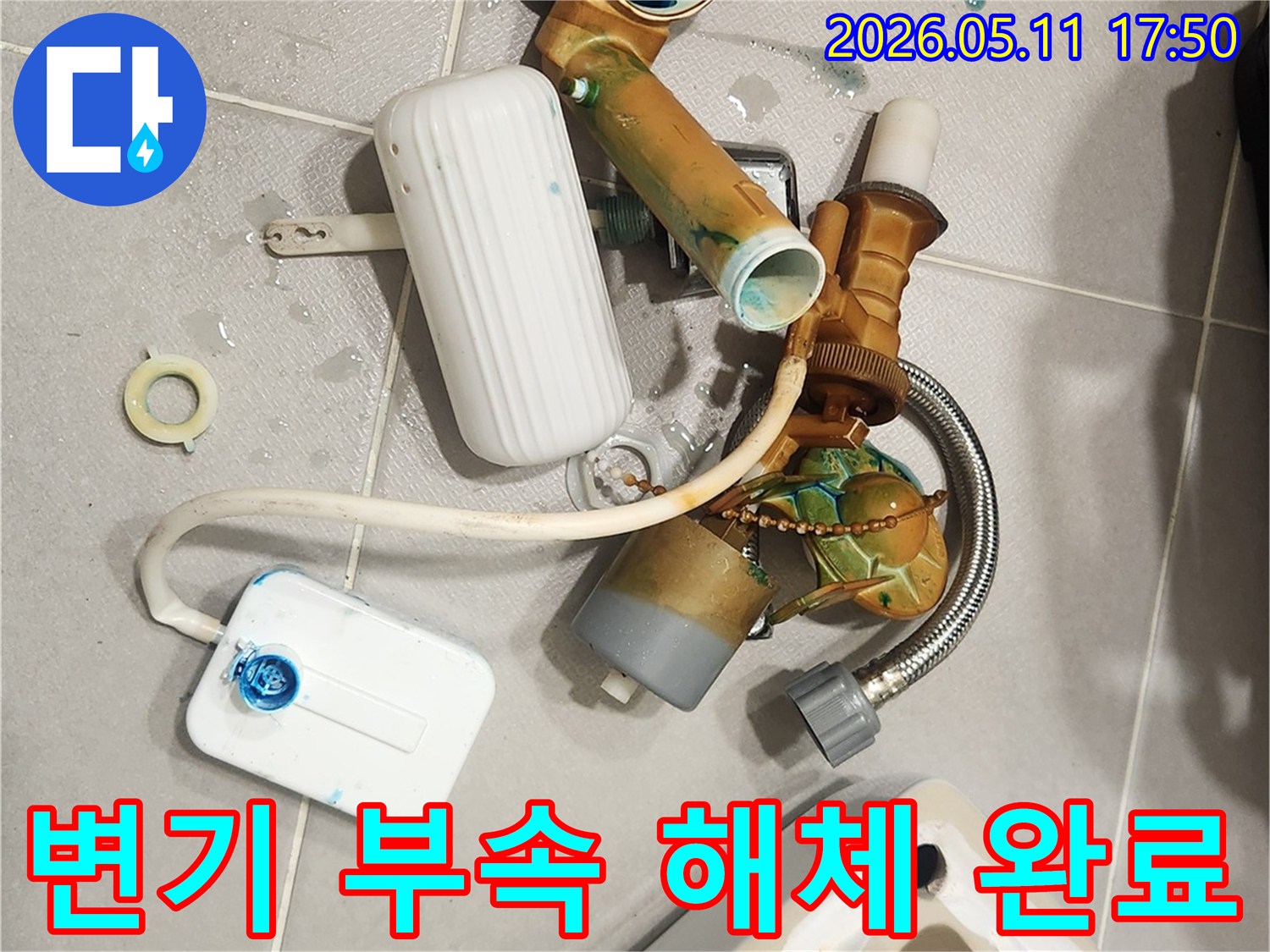 안방 변기에서 발생한 누수 문제로 인해-낡고 부식된 변기 부속들이 해체되어 바닥에 놓여 있는 모습입니다-새 부품으로 교체하여 문제를 해결할 준비가 완료되었습니다