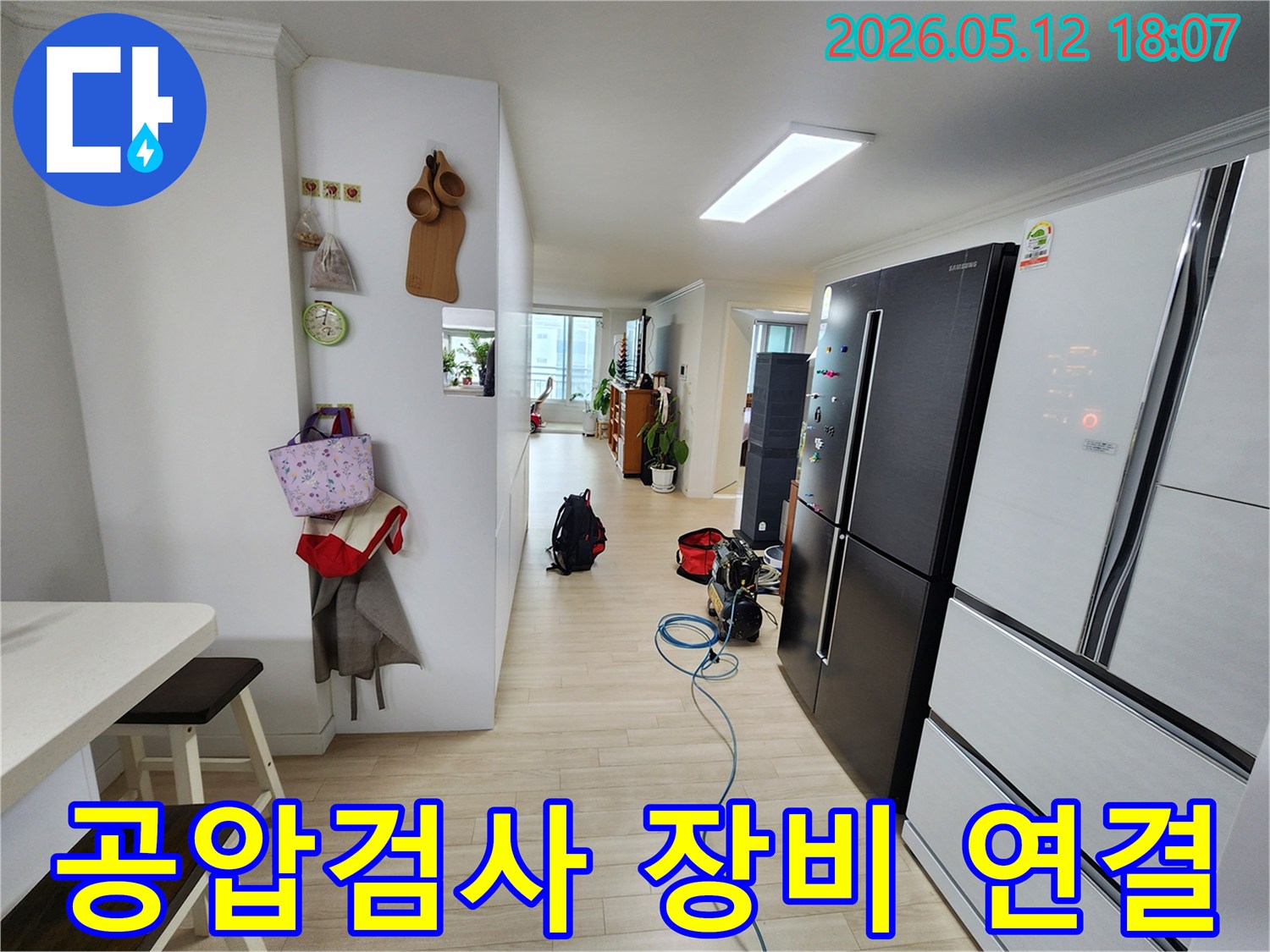 누수 탐지를 위한 공압검사 장비가-거실 바닥에 놓여 있고-호스가 연결된 상태